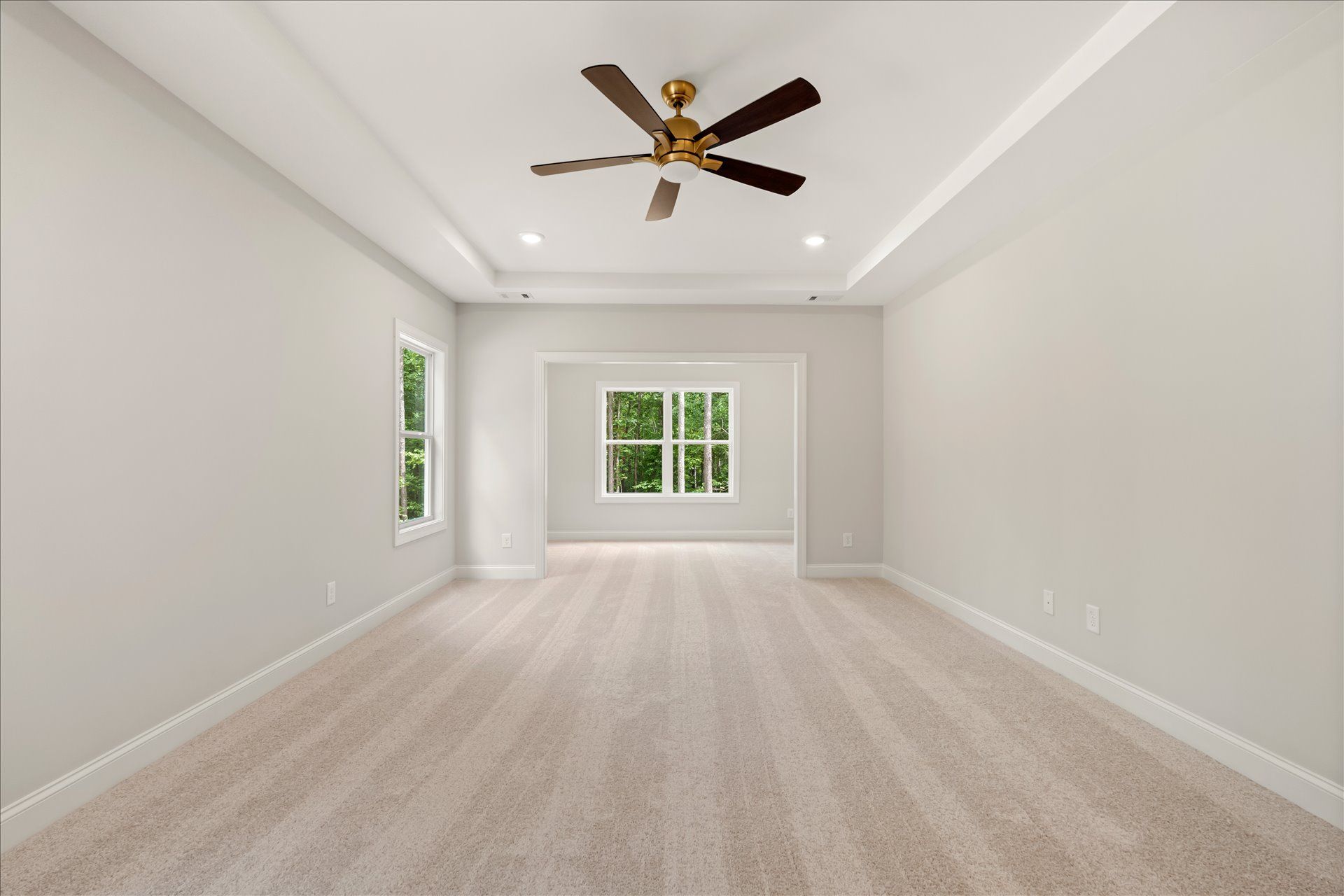 Empty bright room with white walls, beige carpet, recessed lights, and a ceiling fan