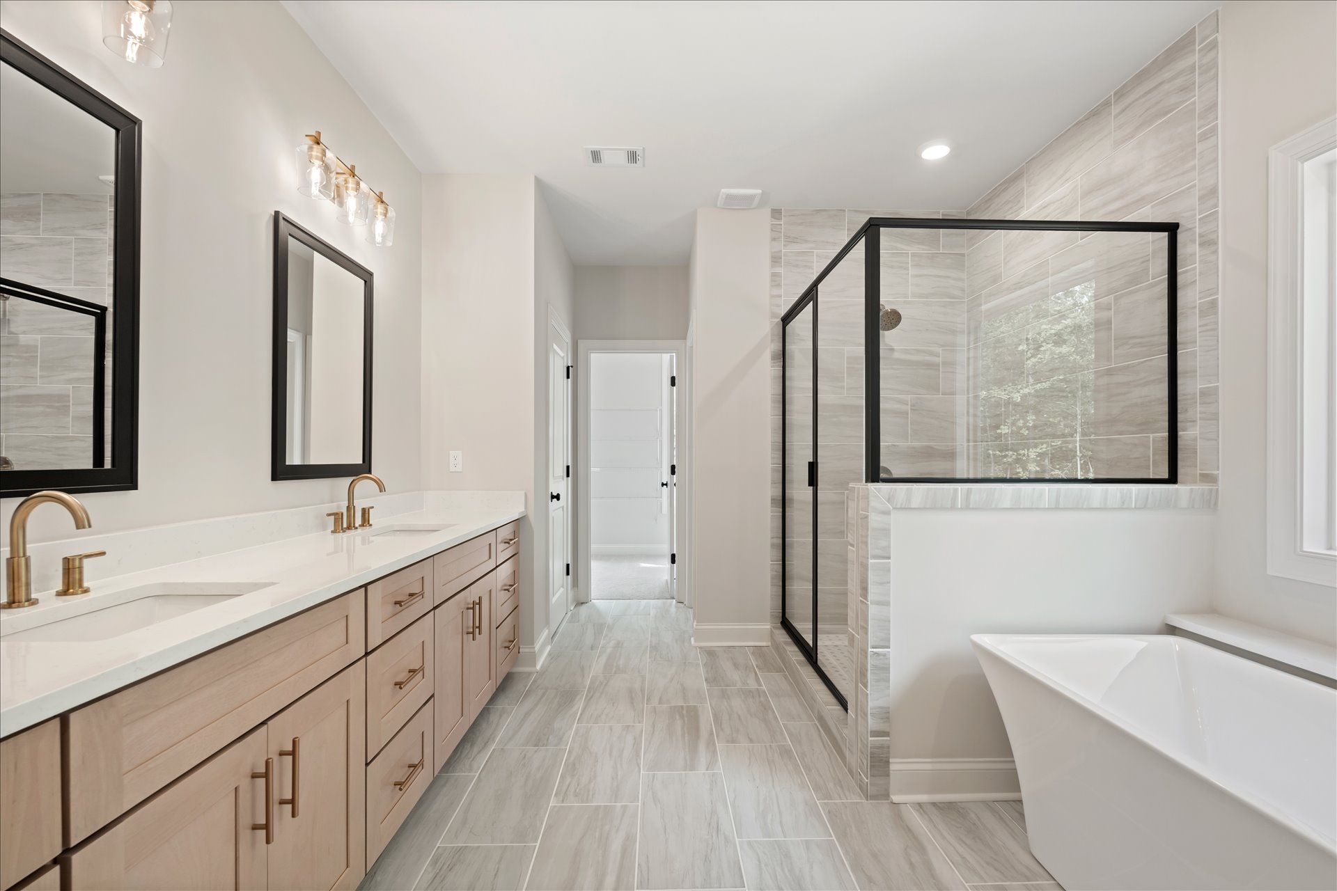 Bright modern bathroom with double vanity, large mirrors, glass shower, and white marble finishes