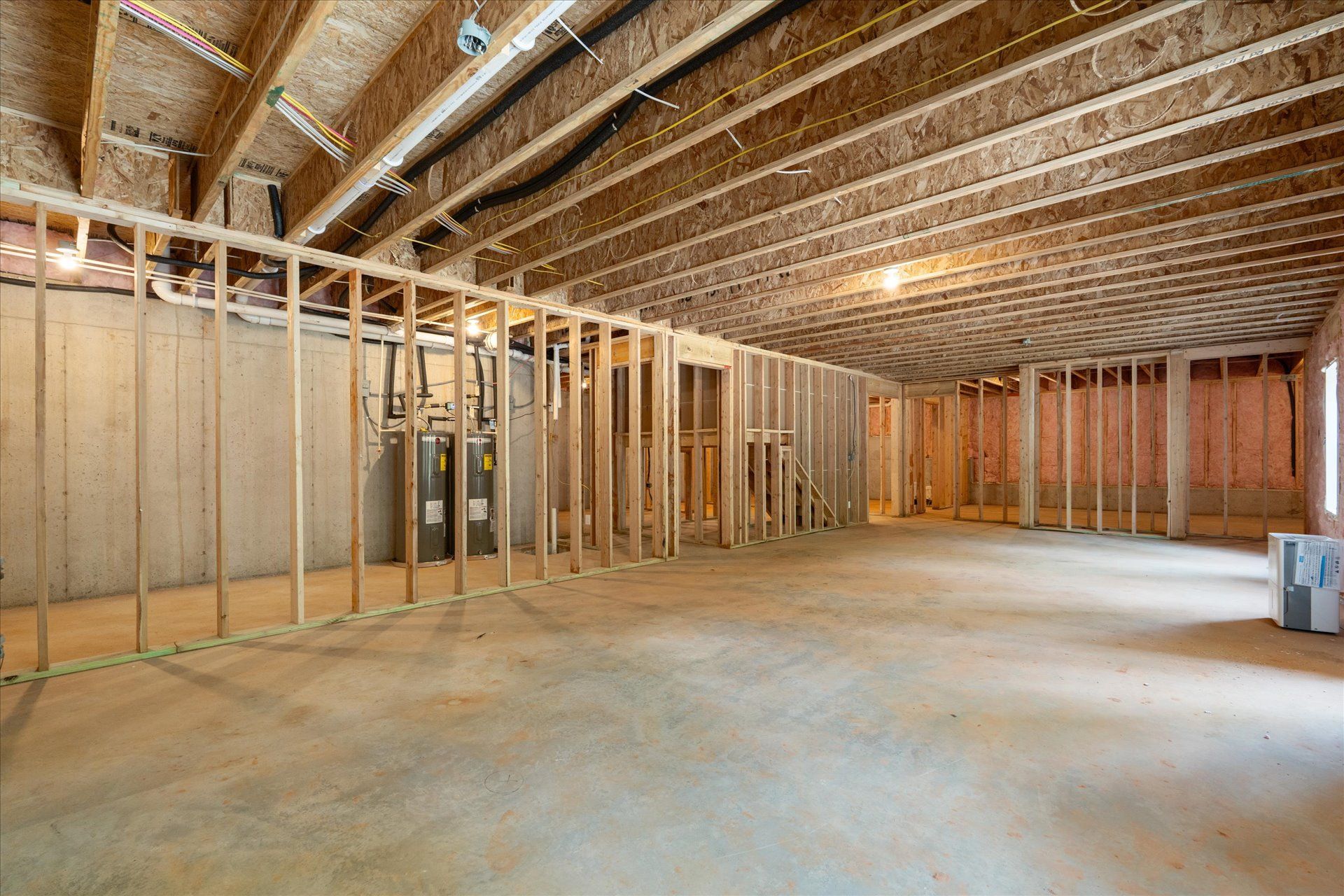 Empty unfinished basement with exposed wooden framing and concrete floor