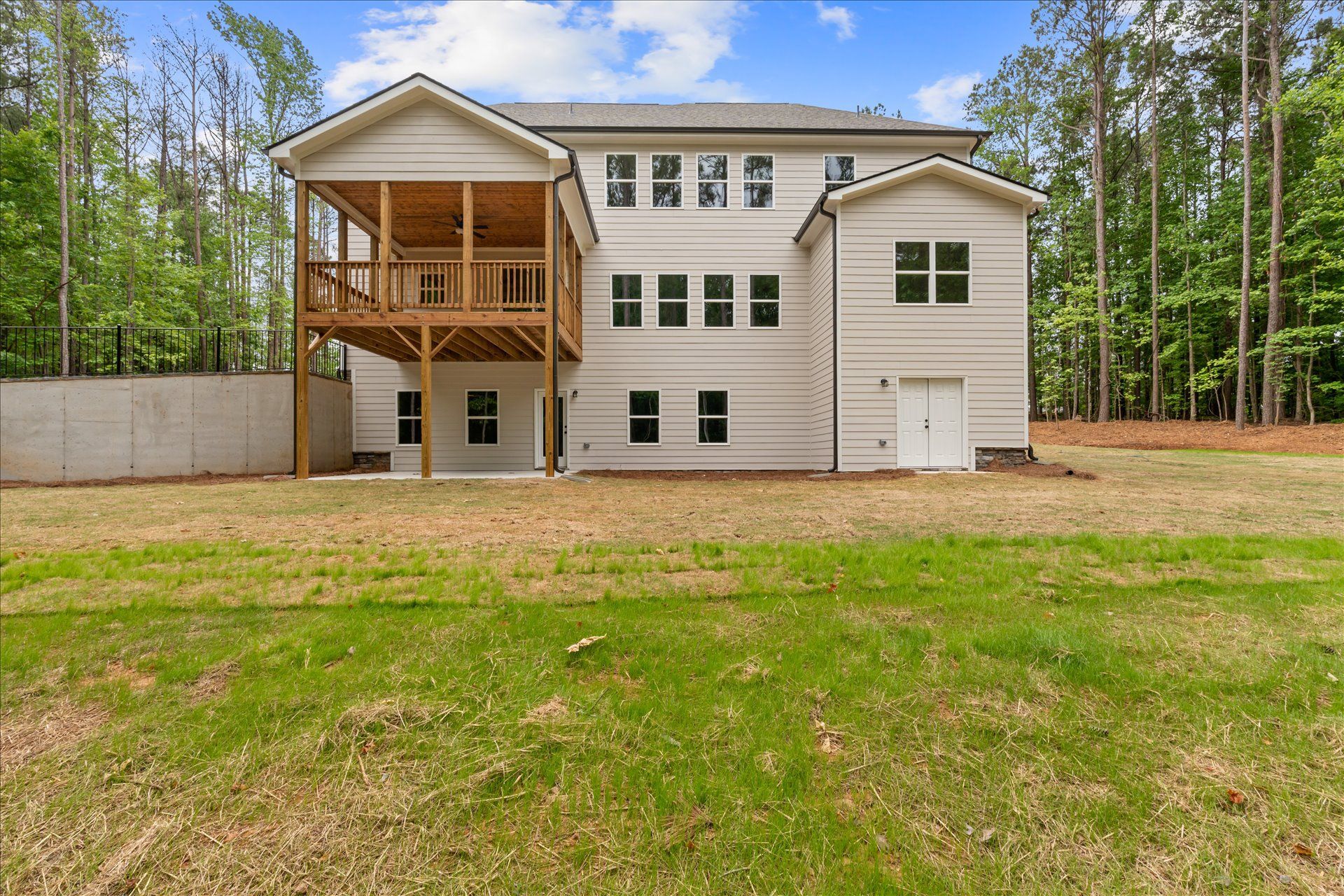 Two-story white house with a covered wooden porch, set on a grassy lot with trees in the background.
