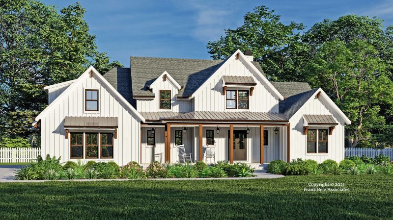 Modern white farmhouse with black roof and porch, set on a green lawn with trees behind.