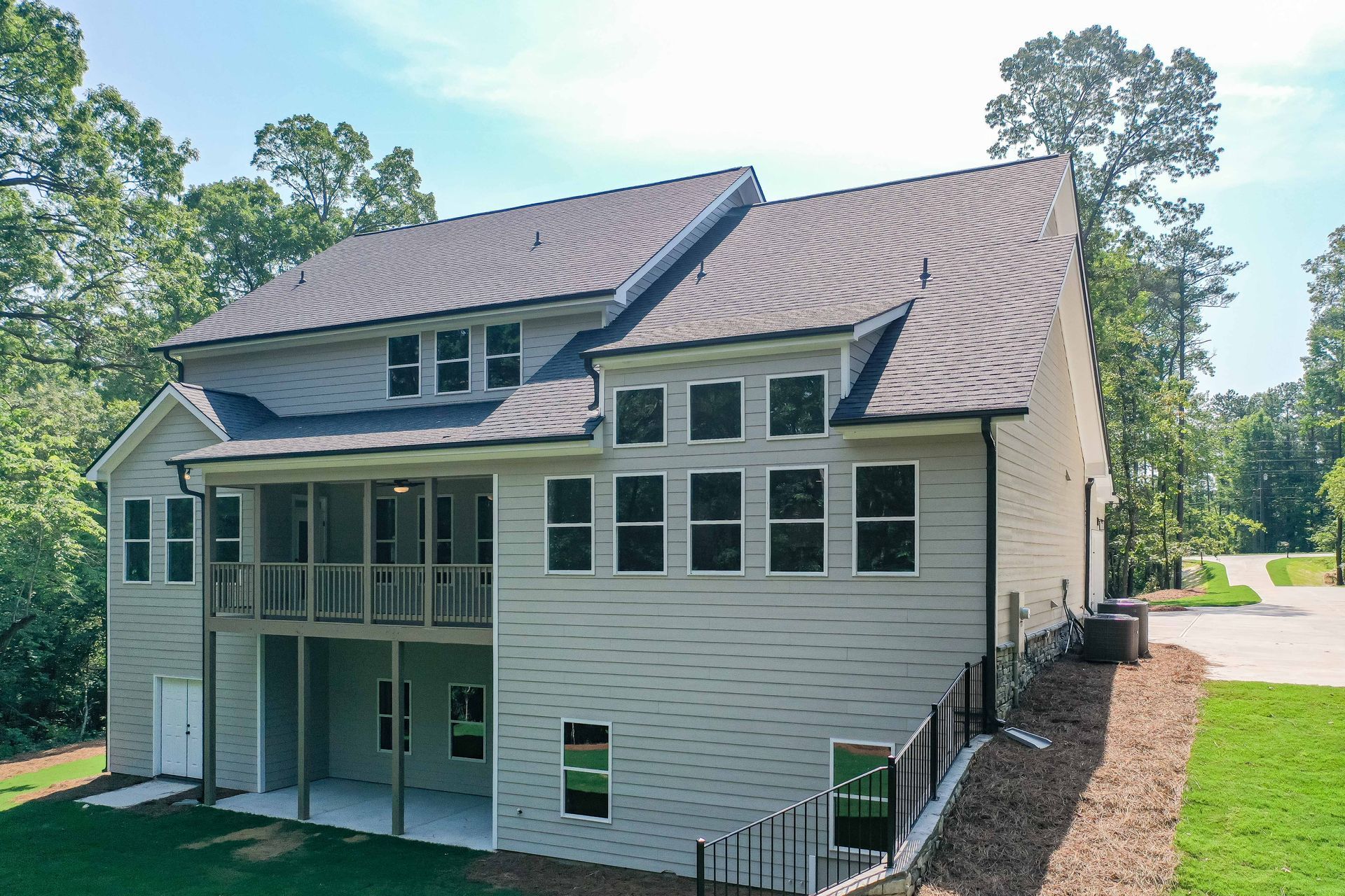Two-story cream house with brown roof and screened porch, viewed from the backyard lawn