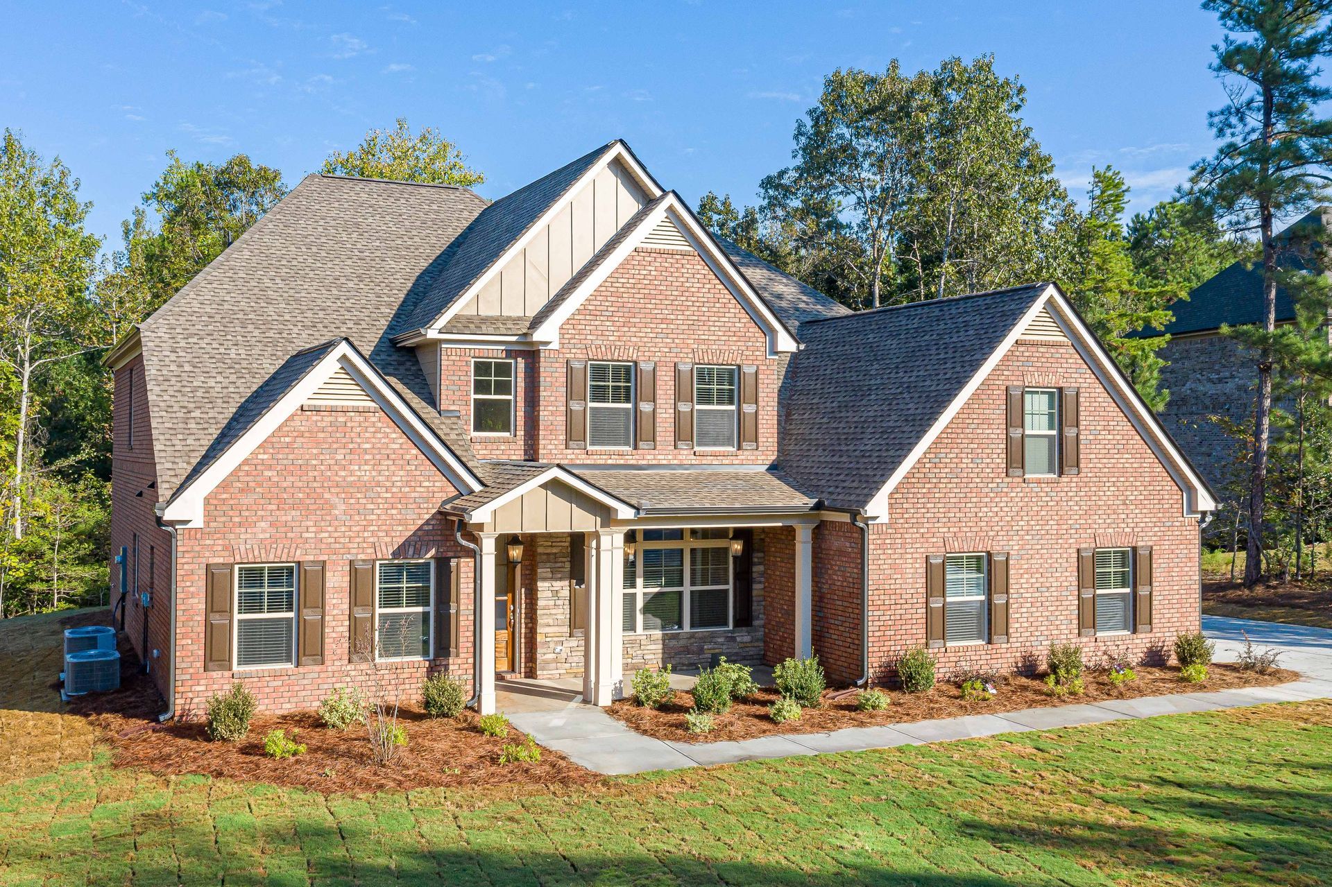 Brick suburban house with gabled roof, white trim, and front porch on a sunny day
