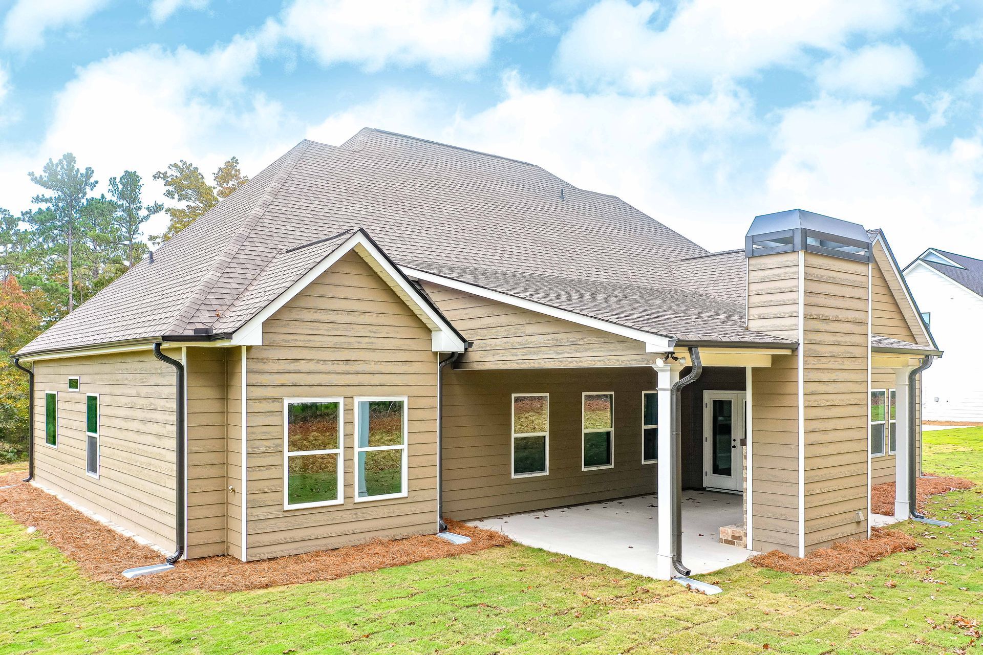 Modern single-story brick house with a gray roof and covered patio in a grassy yard