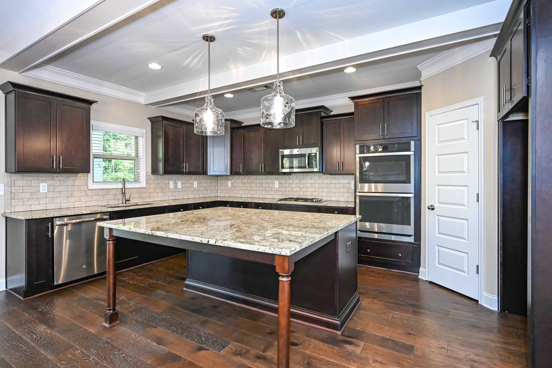 Modern kitchen with dark cabinets, granite island, stainless appliances, and hardwood floors