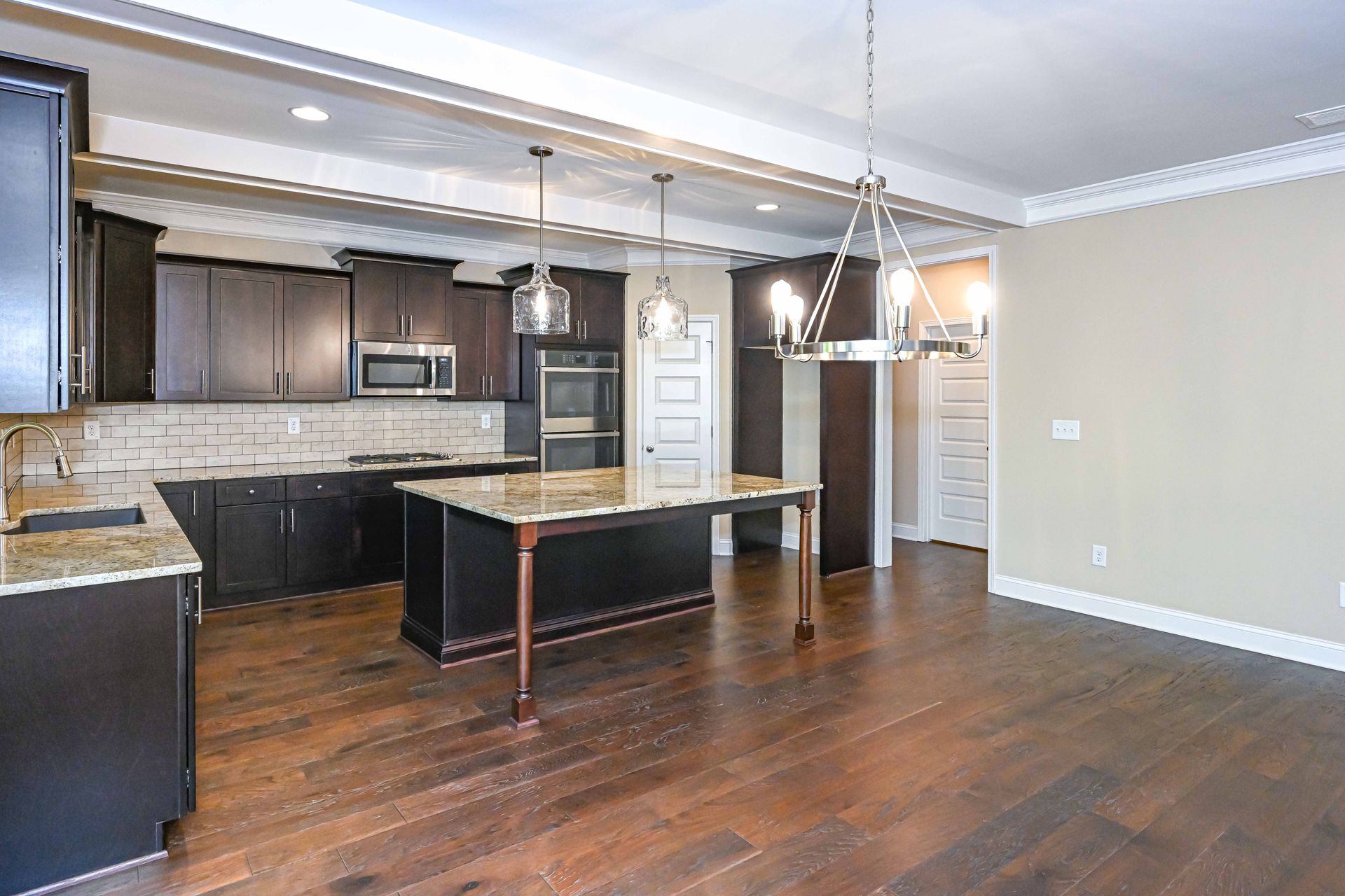 Modern kitchen with dark wood cabinets, island, stainless appliances, and hardwood floors