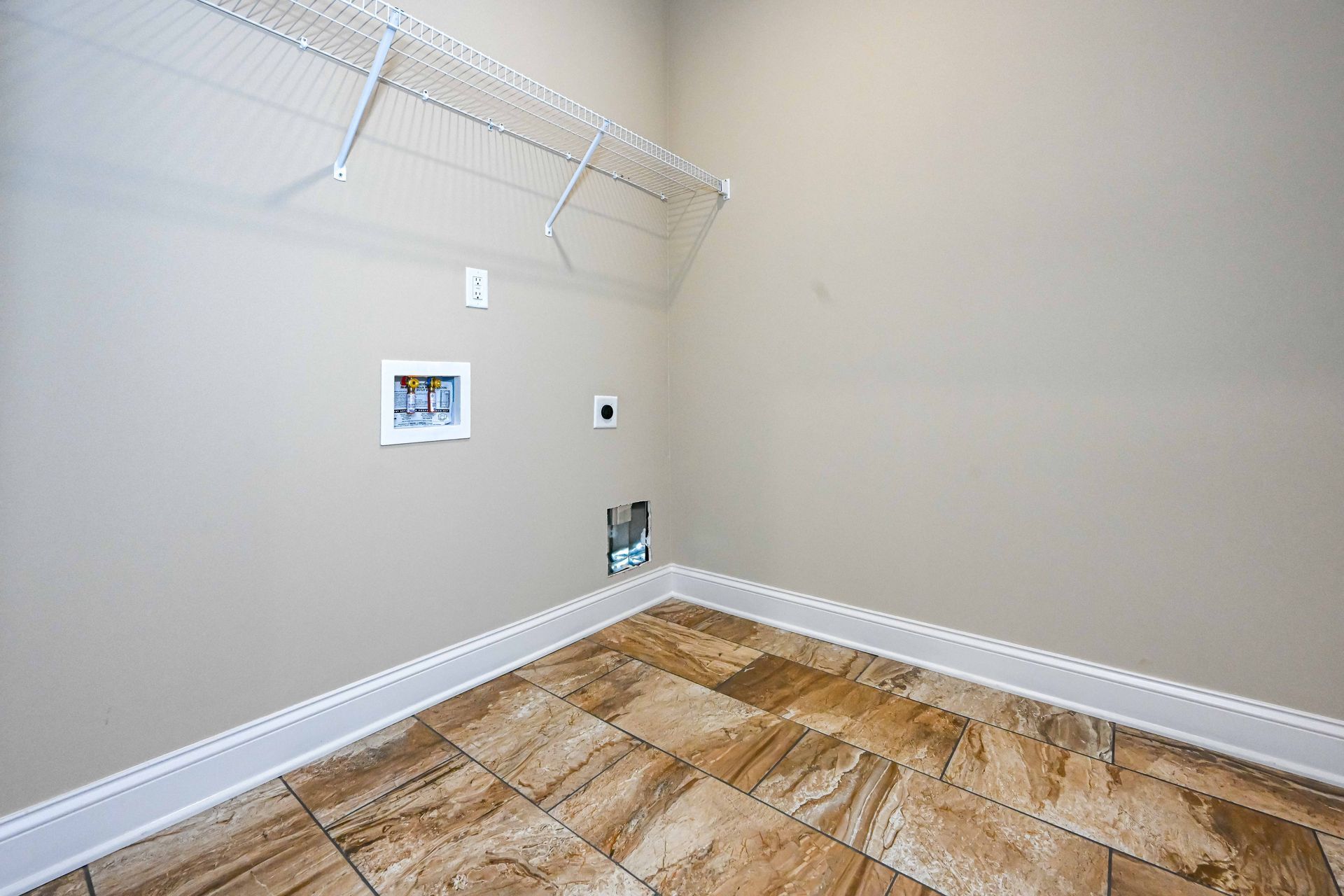 Empty walk-in closet with white wire shelves, beige walls, and wood-look flooring.