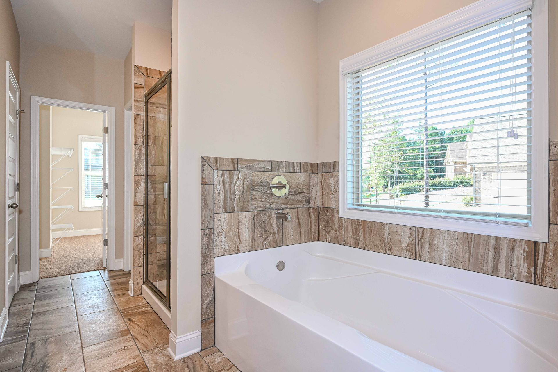 Modern bathroom with a bathtub, tiled shower, large window, and glass shower enclosure.