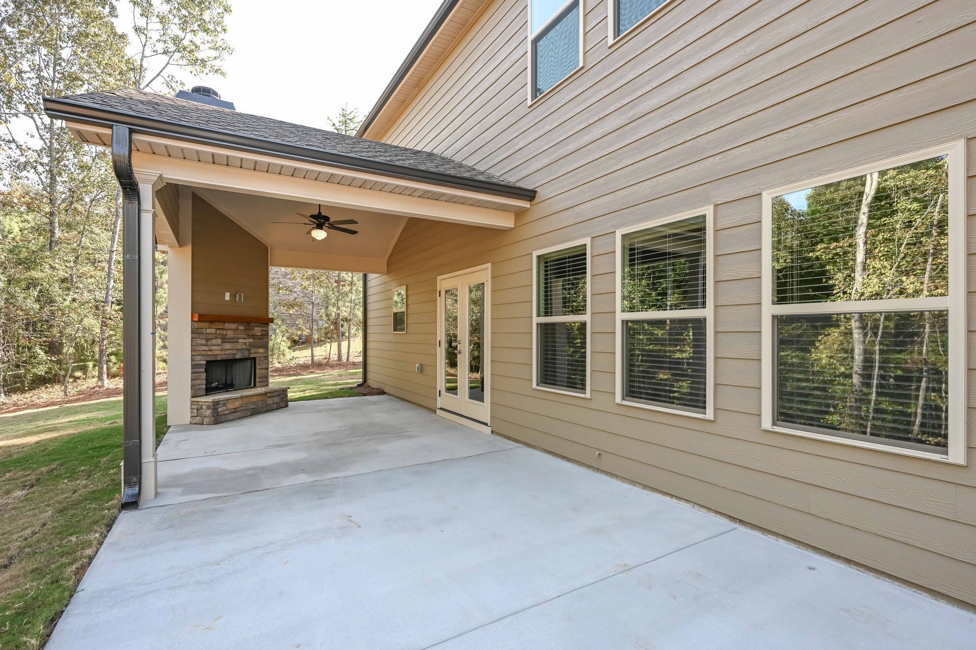 Covered backyard patio beside beige house with concrete slab and windows