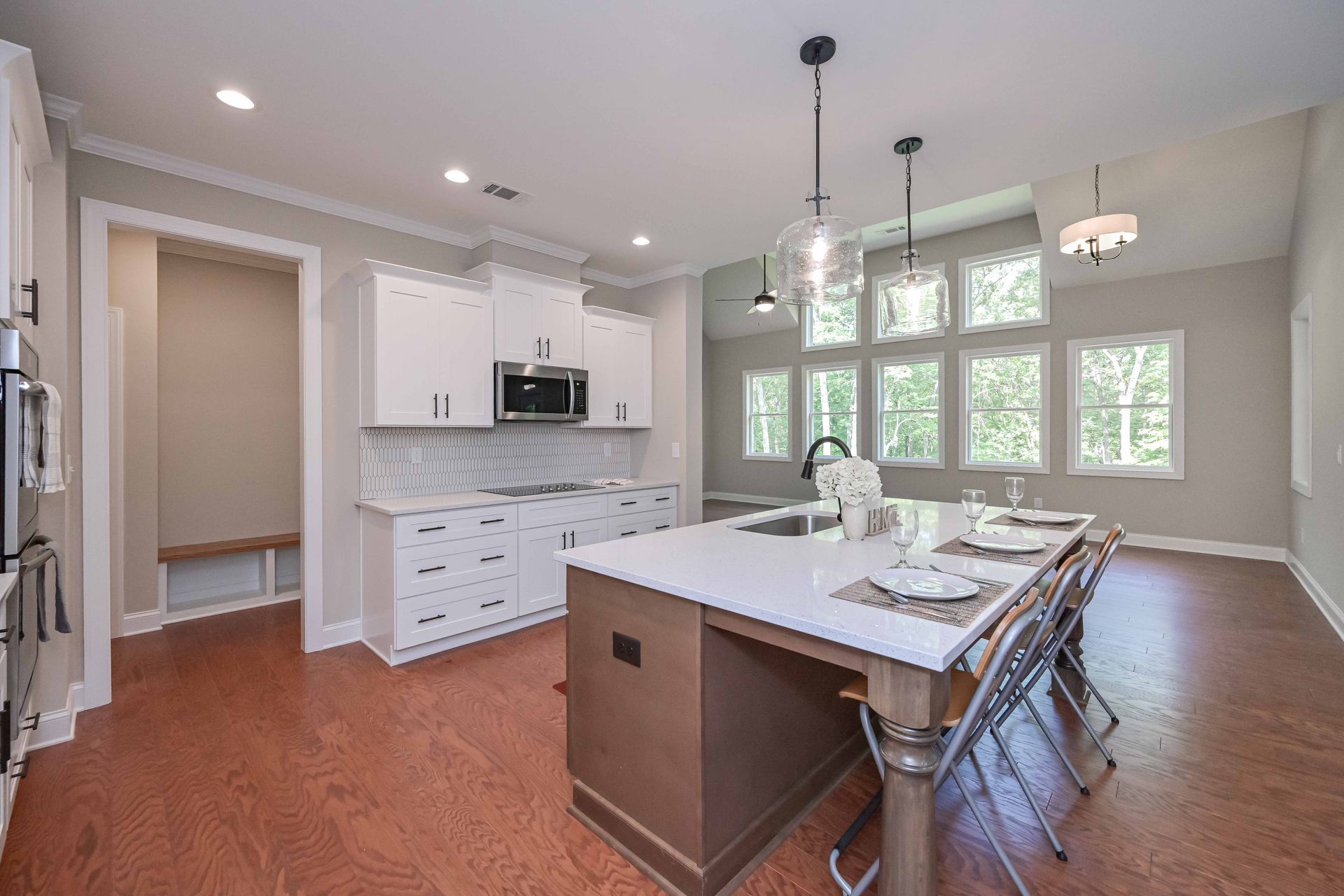 Bright modern kitchen with white cabinets, island, and large windows over hardwood floors
