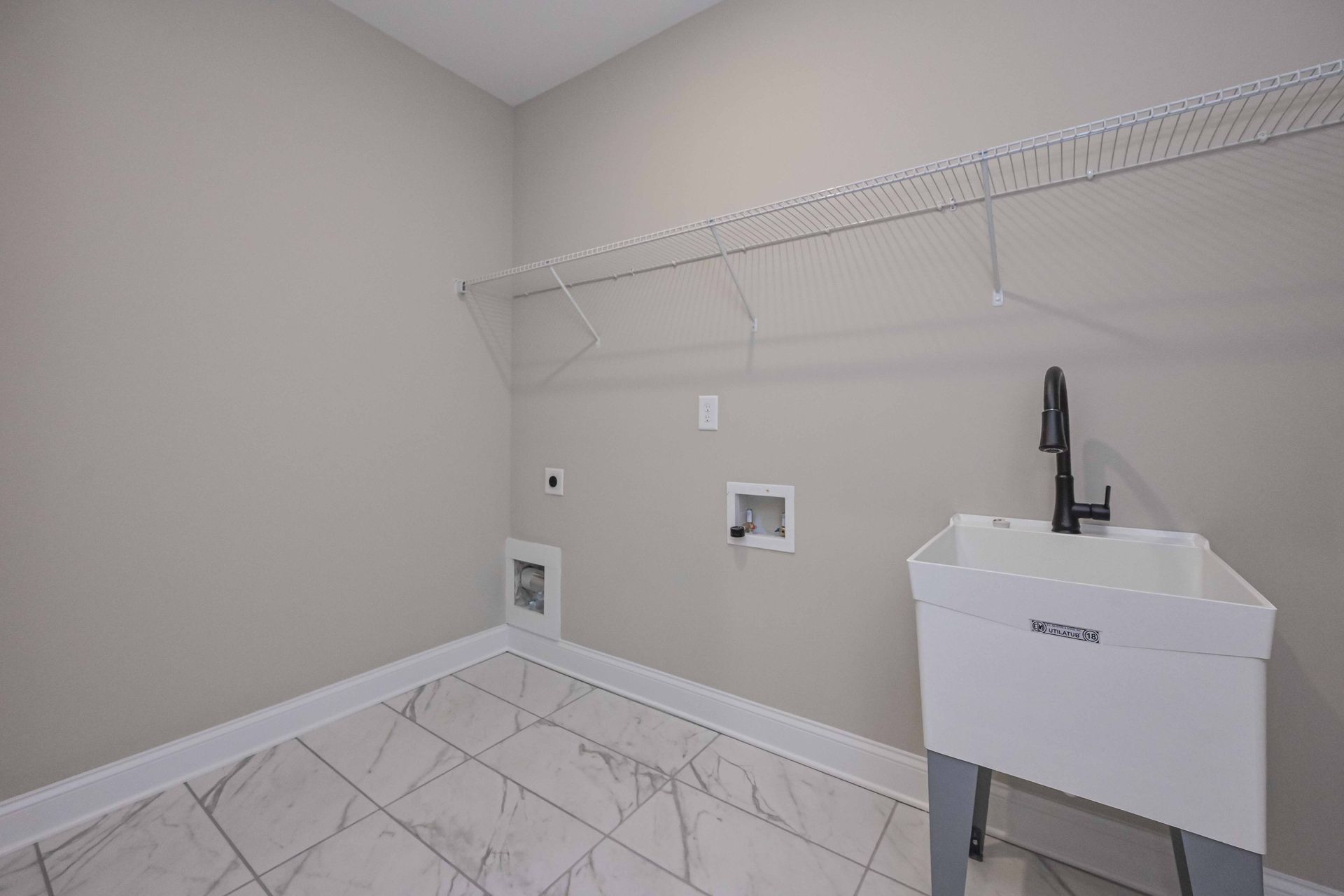 Laundry room with wire shelving, utility sink, and tiled floor.