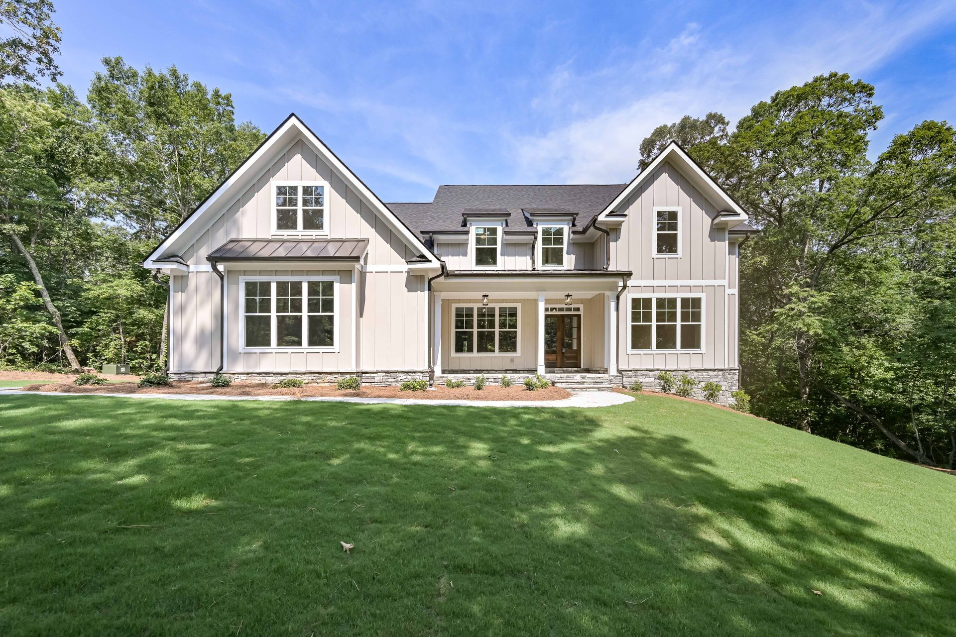 Large two-story suburban house with gray siding, white trim, and a green front lawn