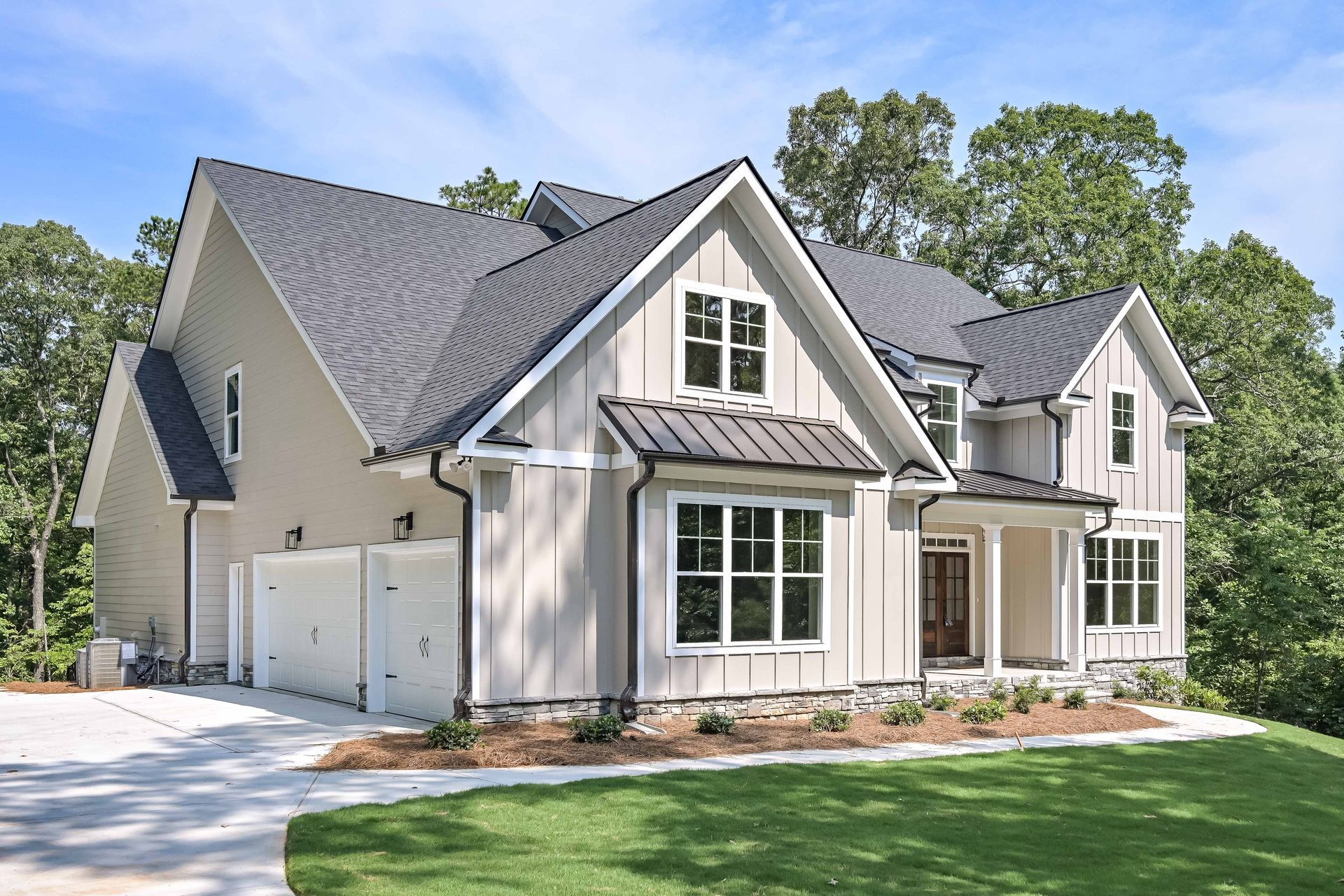 Large modern two-story suburban house with gray siding, white trim, and a two-car garage on a landscaped lawn