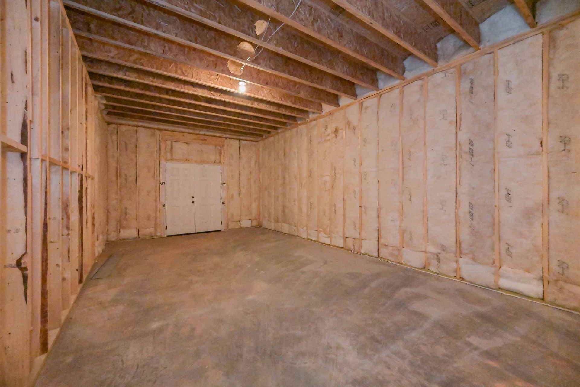 Empty unfinished basement with exposed wooden framing and a concrete floor