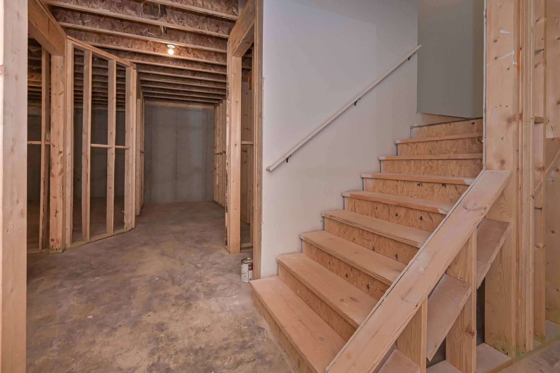 Unfinished interior with exposed framing and a wooden staircase under construction