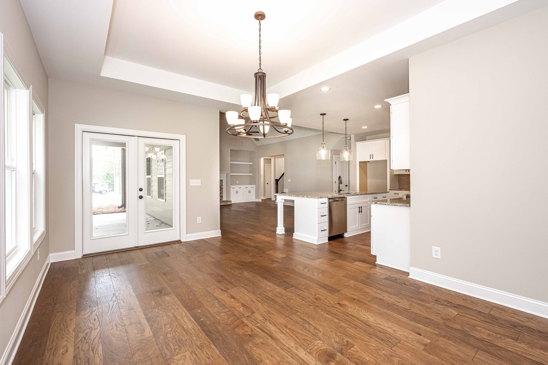 Bright open kitchen and dining area with hardwood floors, white walls, and French doors to a patio.