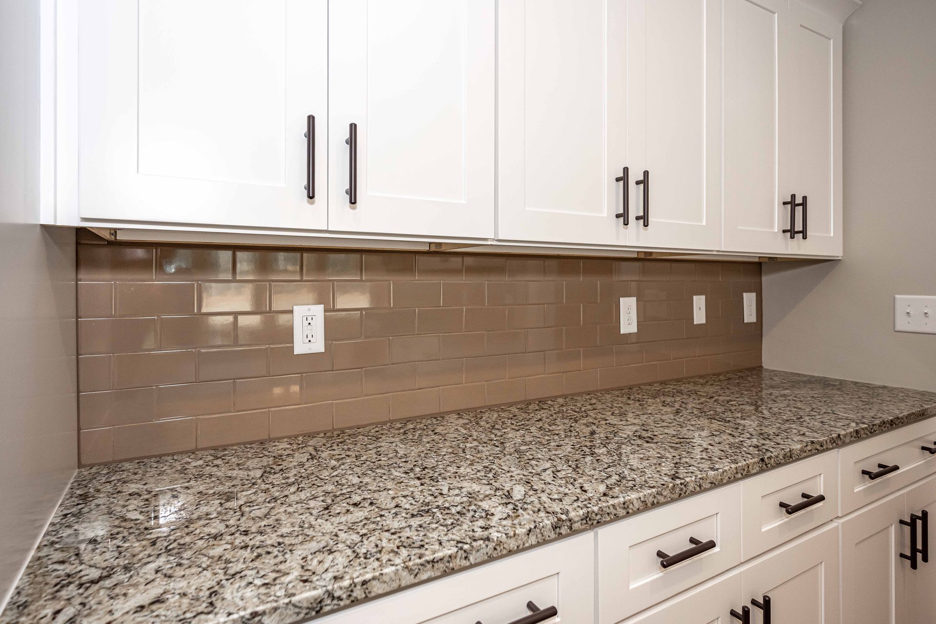 White kitchen cabinets with granite countertop and beige tile backsplash underneath
