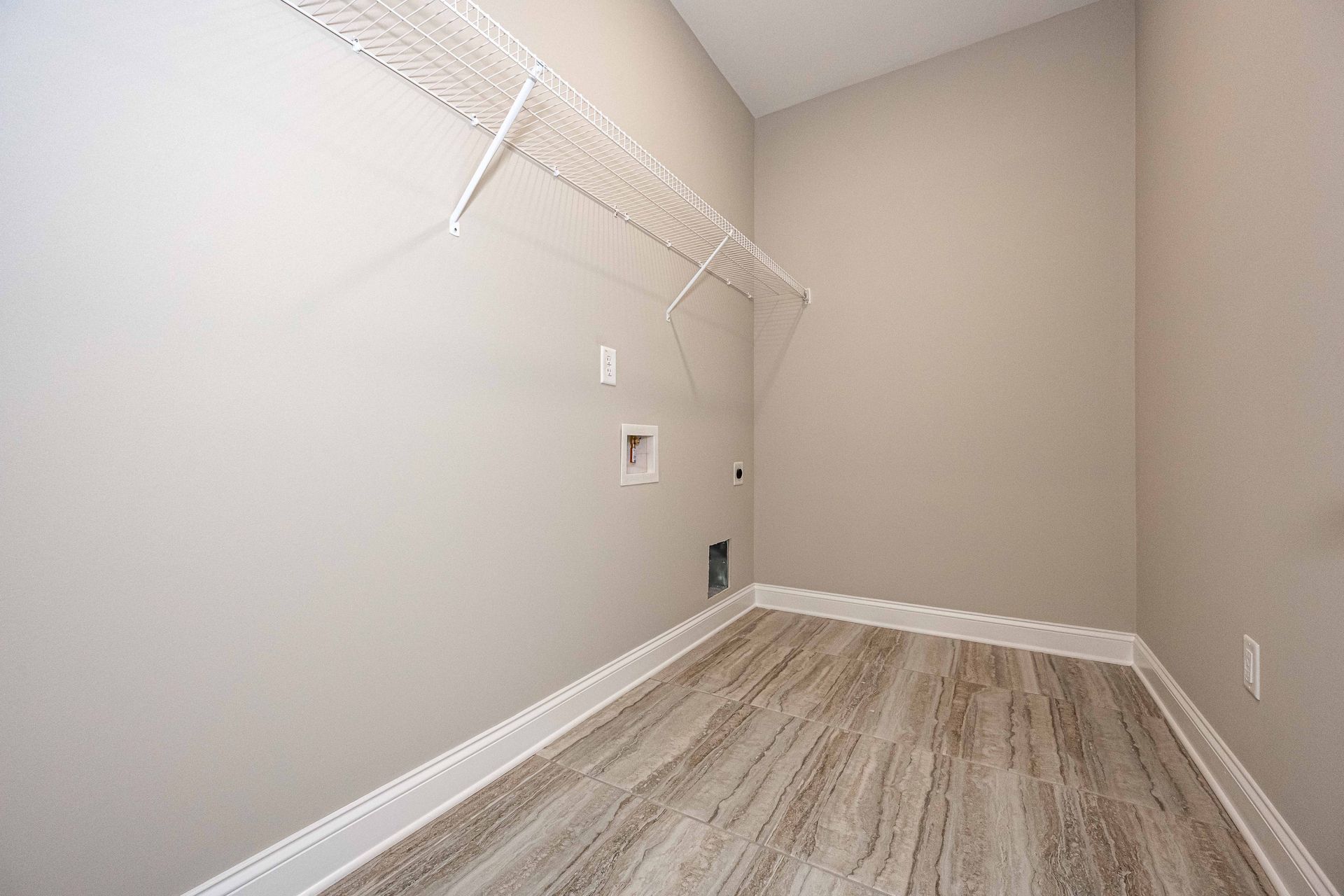 Empty walk-in closet with beige walls, white wire shelving, and wood-patterned flooring.