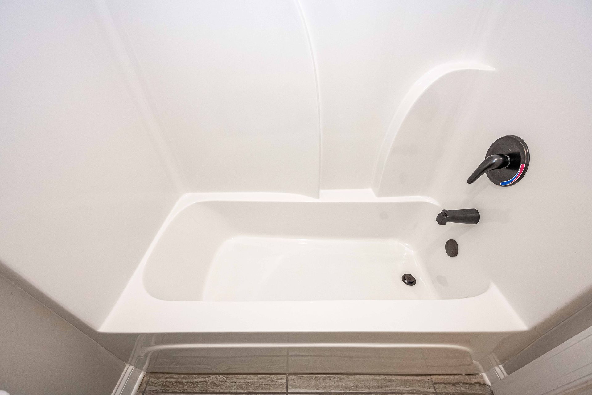 White bathtub with shower faucet and built-in shelf in a bathroom.