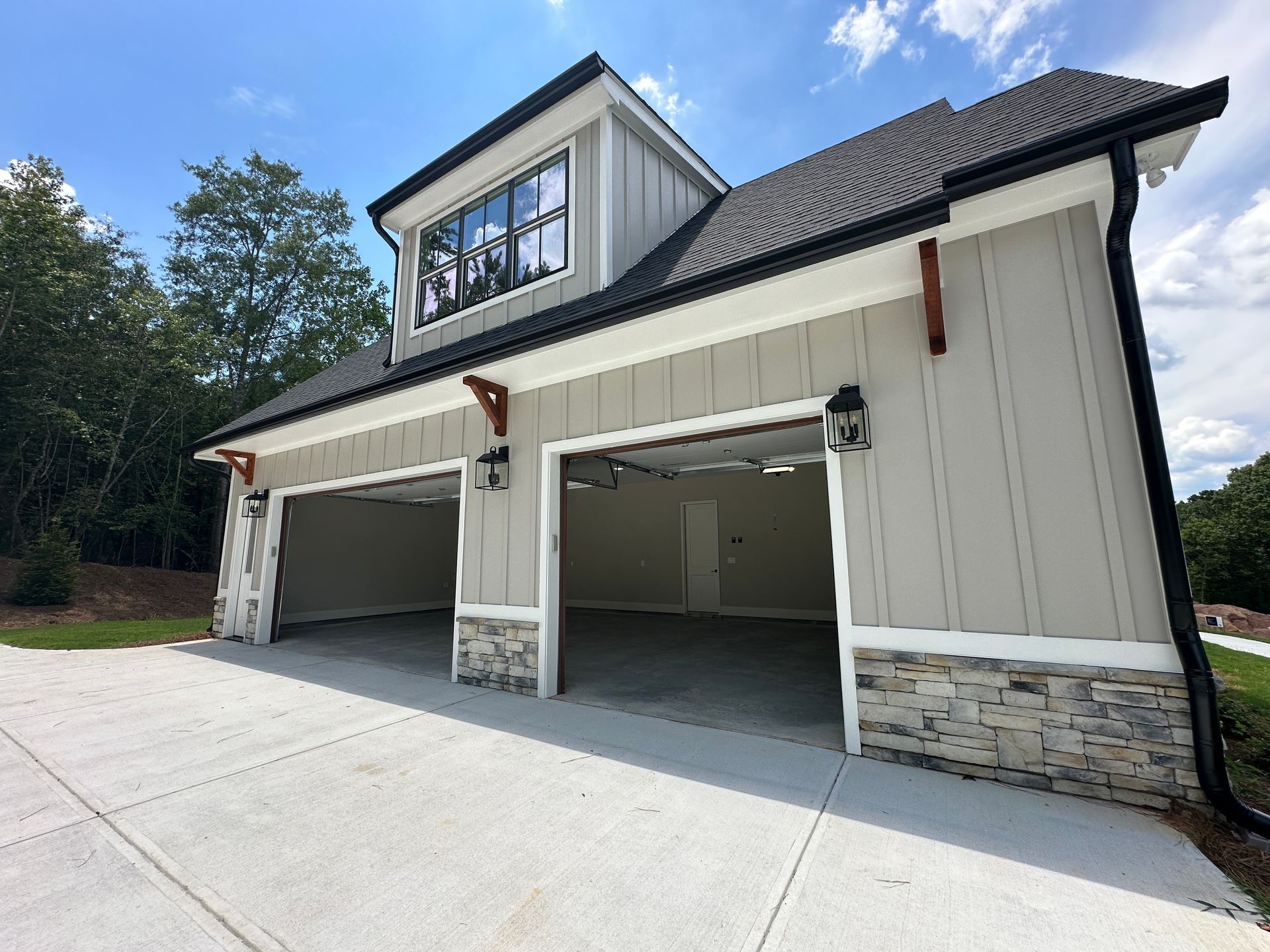 Two-story white garage with stone accents and two open bays under a clear sky