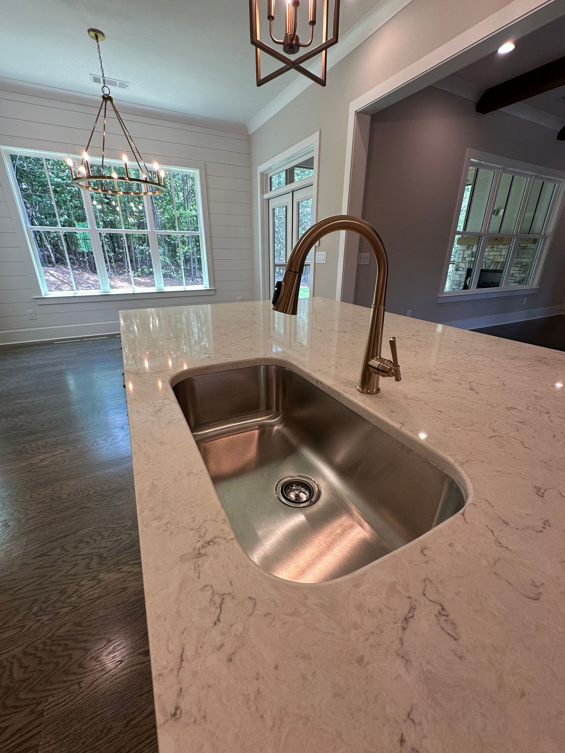 Kitchen island with stainless steel sink and high-arc faucet in a bright open-plan home