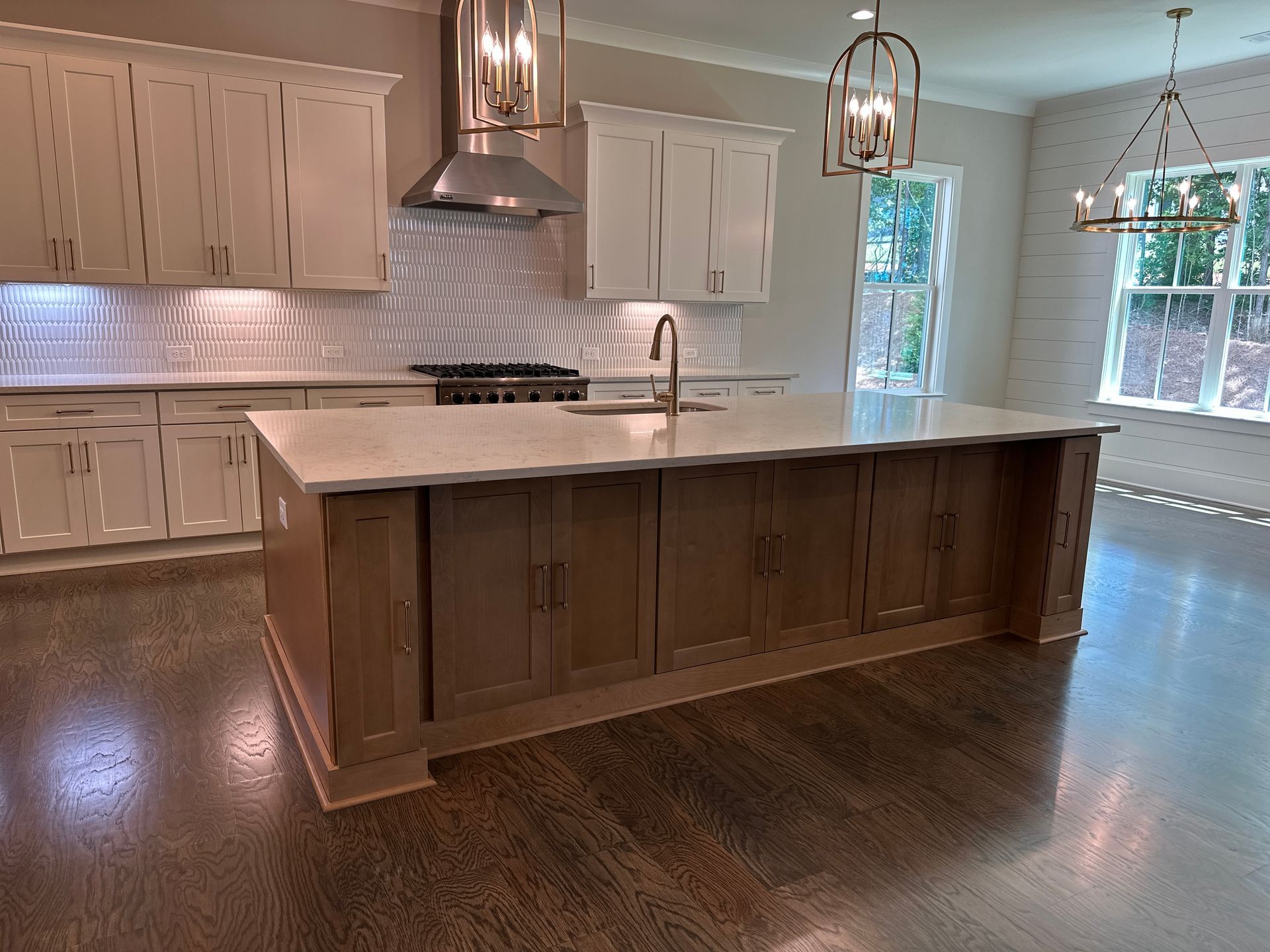Modern kitchen with a large wood island, white cabinets, stainless range hood, and dark hardwood floors