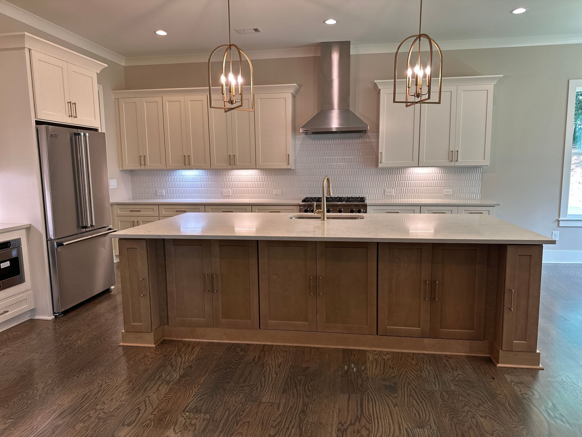 Modern kitchen with large island, white cabinets, stainless steel appliances, and pendant lights