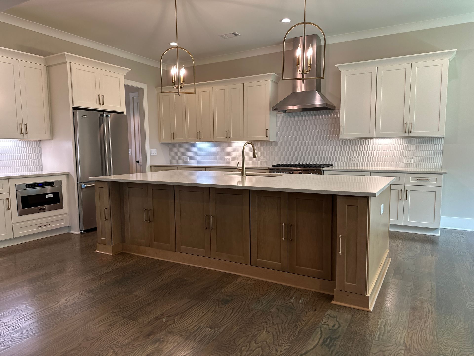 Modern kitchen with white cabinets, large island, stainless appliances, and dark wood floor