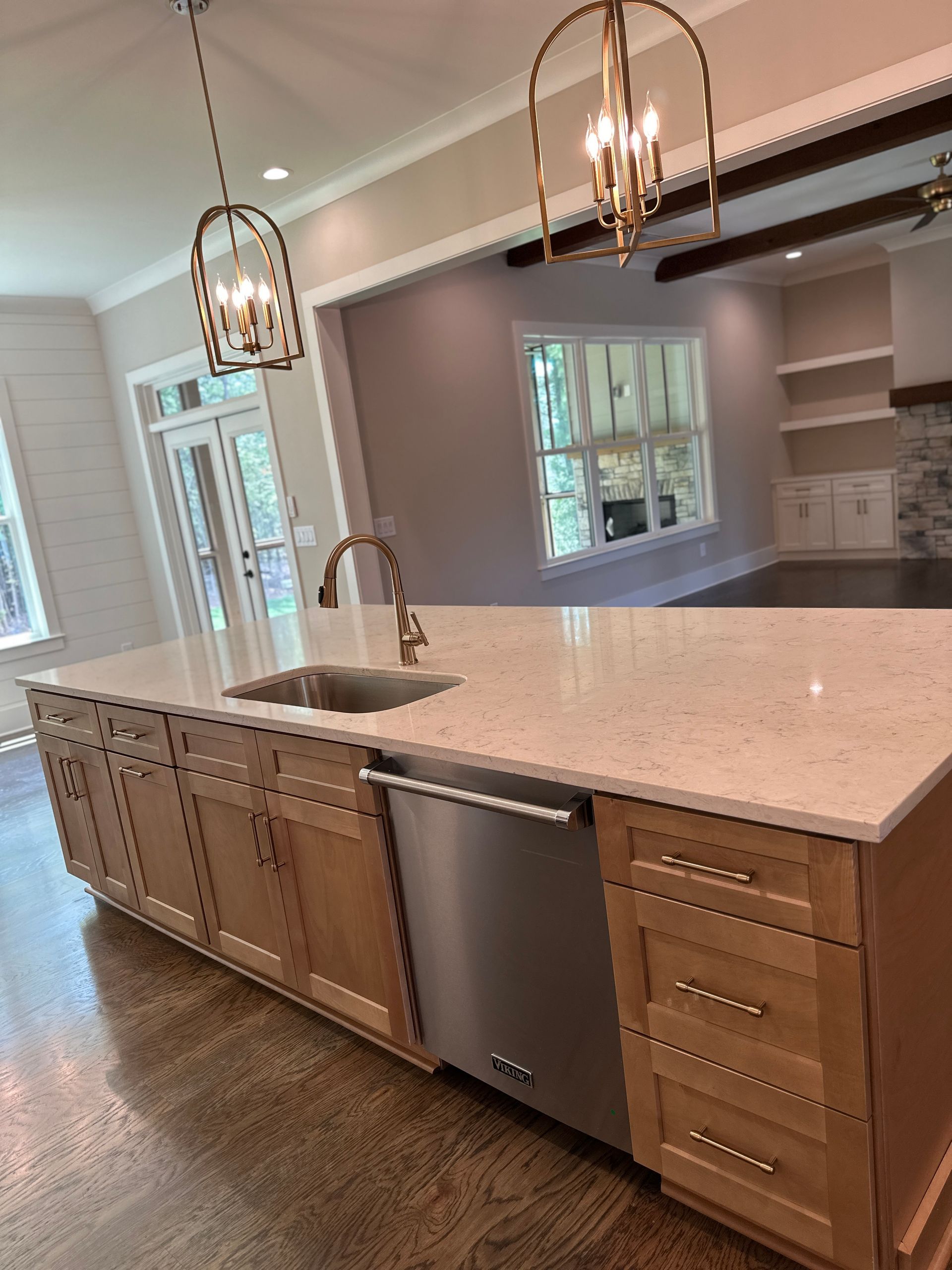 Modern kitchen with large island, stainless dishwasher, white countertop, and pendant lights