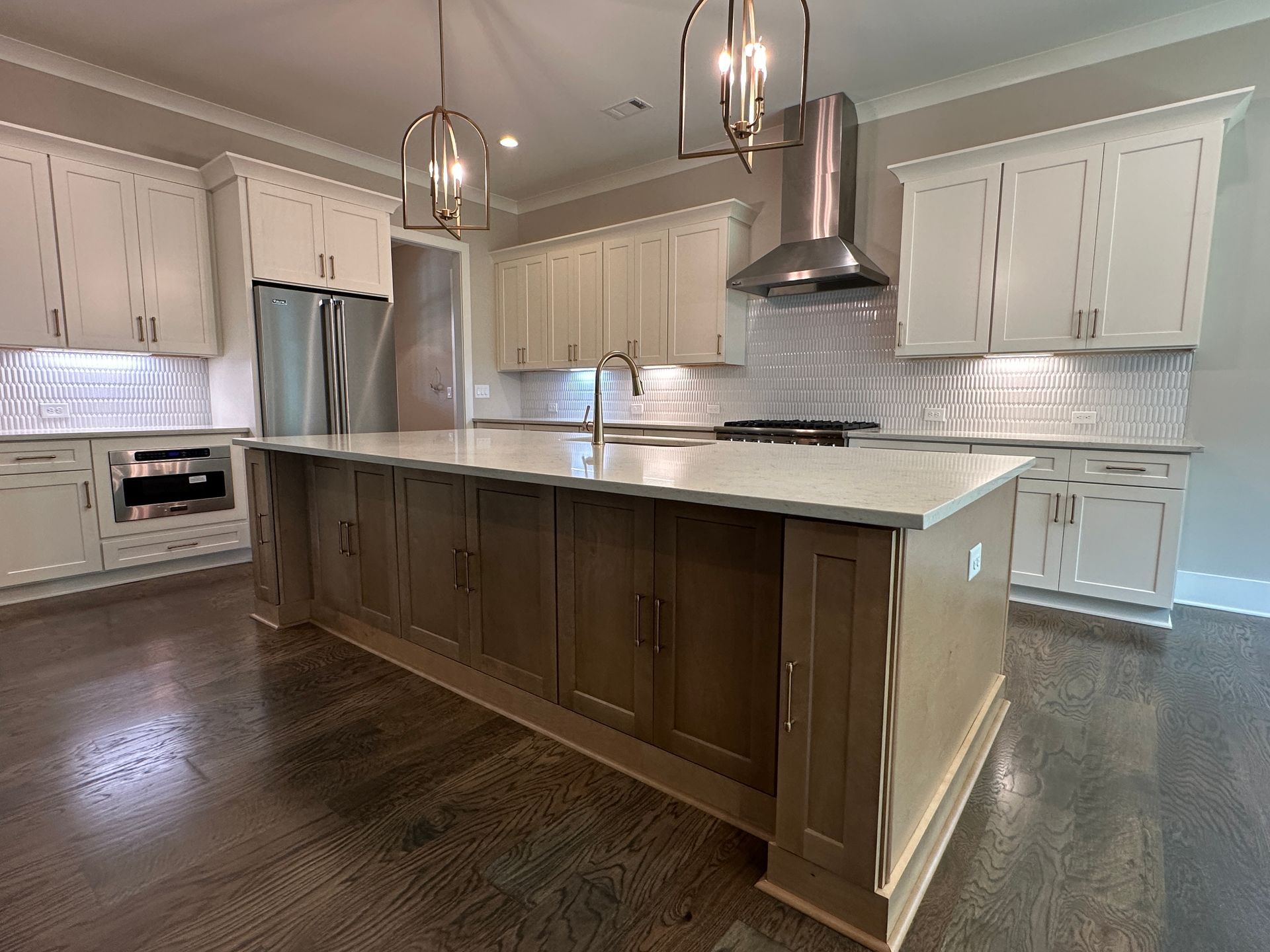 Modern kitchen with large island, white cabinets, stainless steel appliances, and pendant lights