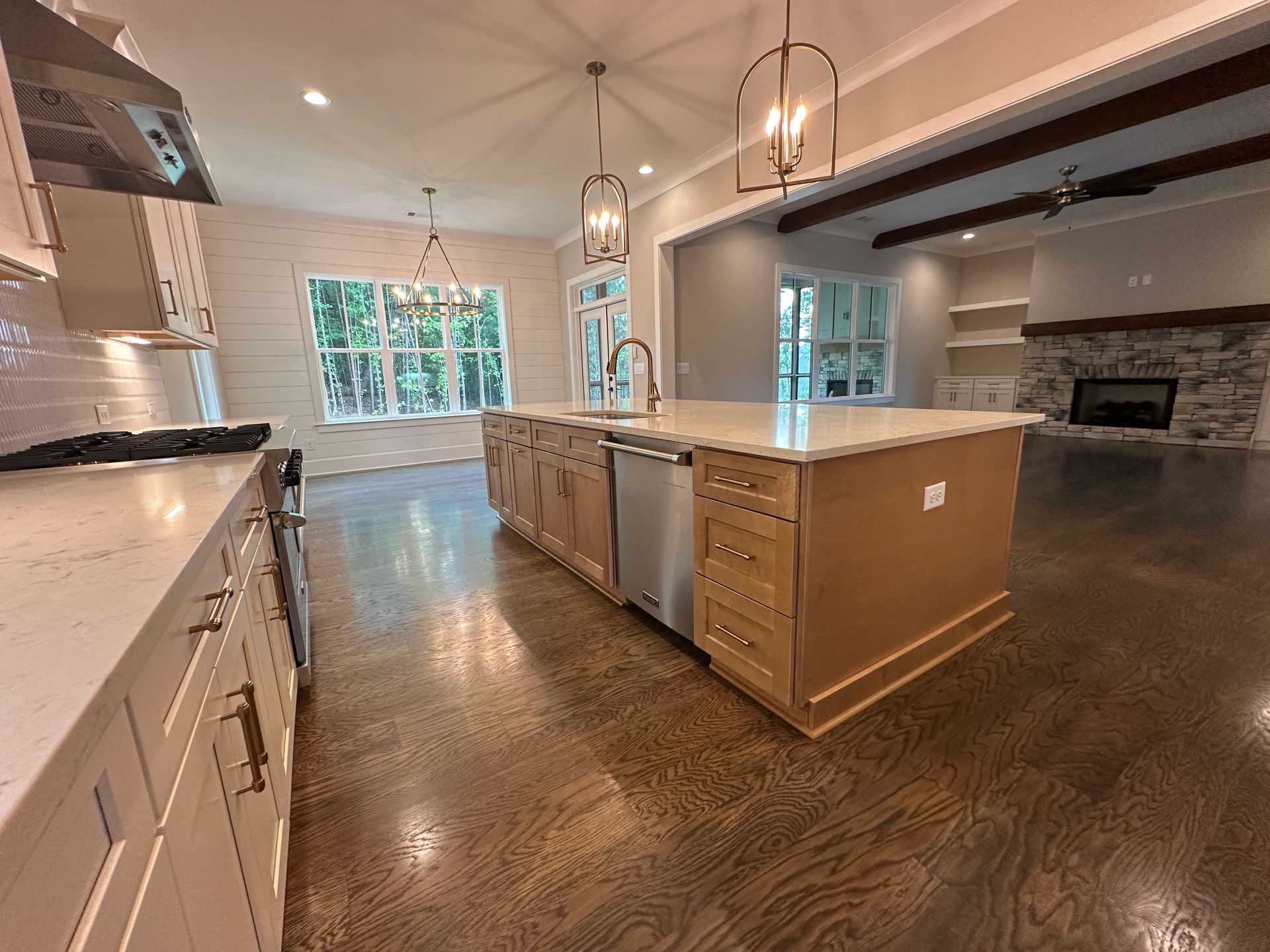 Modern open-concept kitchen with wood flooring, island, pendant lights, and white cabinets
