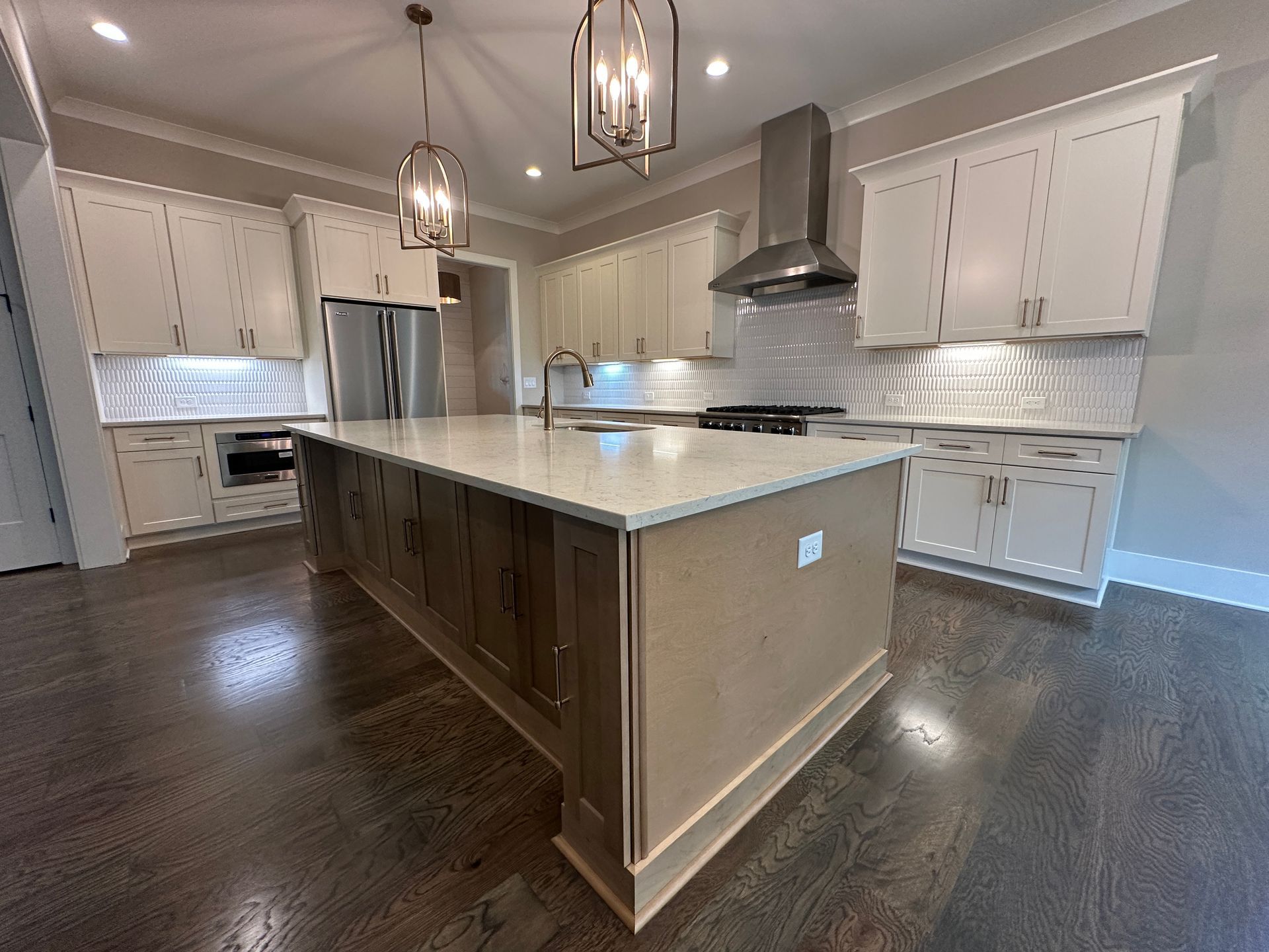 Spacious modern kitchen with white cabinets, large island, pendant lights, and stainless-steel appliances