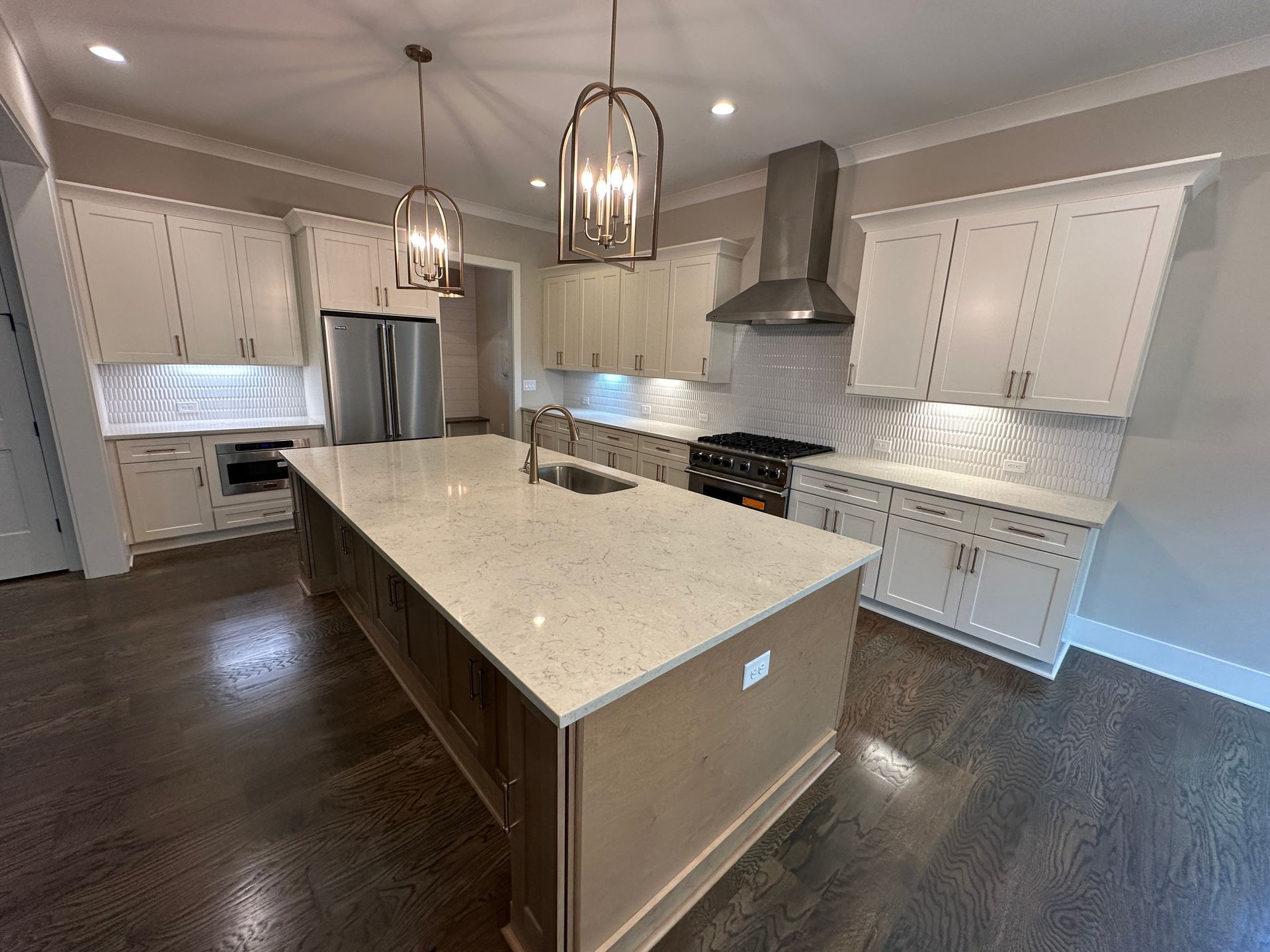Modern kitchen with a large island, white cabinets, stainless appliances, and pendant lights