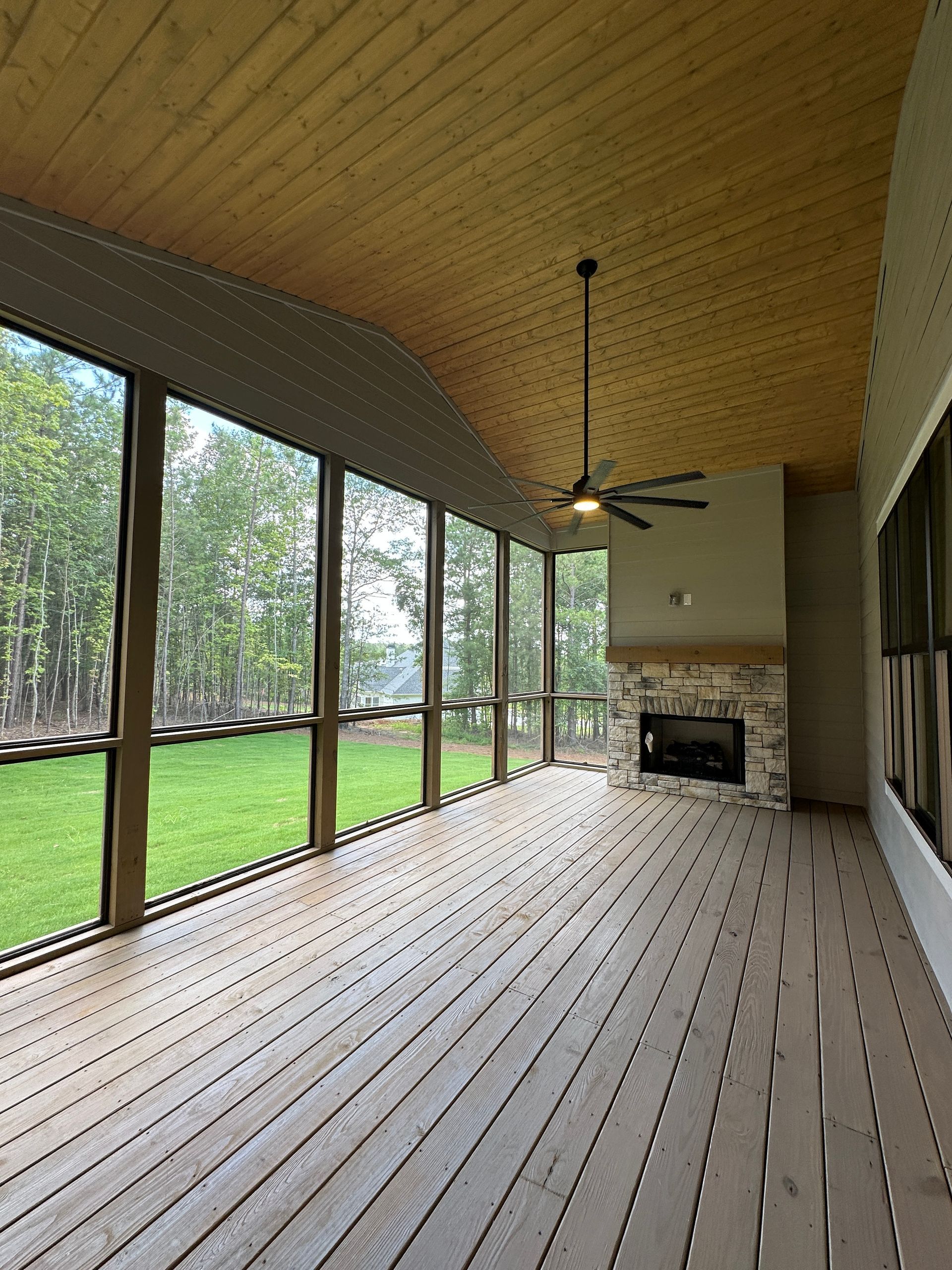 Long screened porch with wood ceiling, ceiling fan, fireplace, and grassy yard view