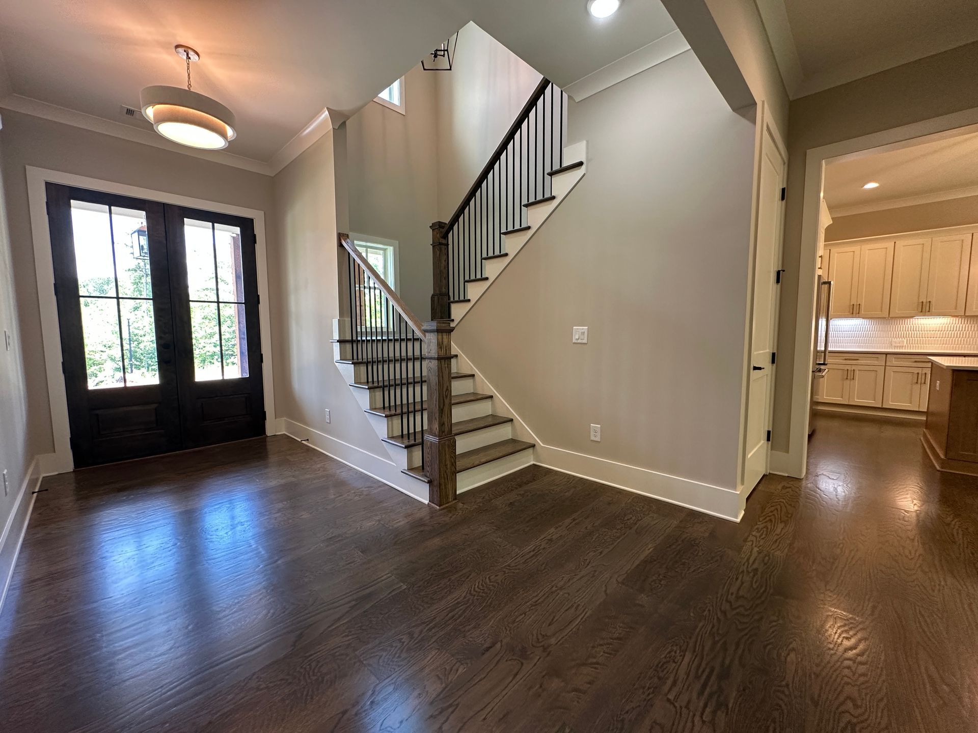 Entryway with dark wood floors, front door, and staircase leading upstairs.