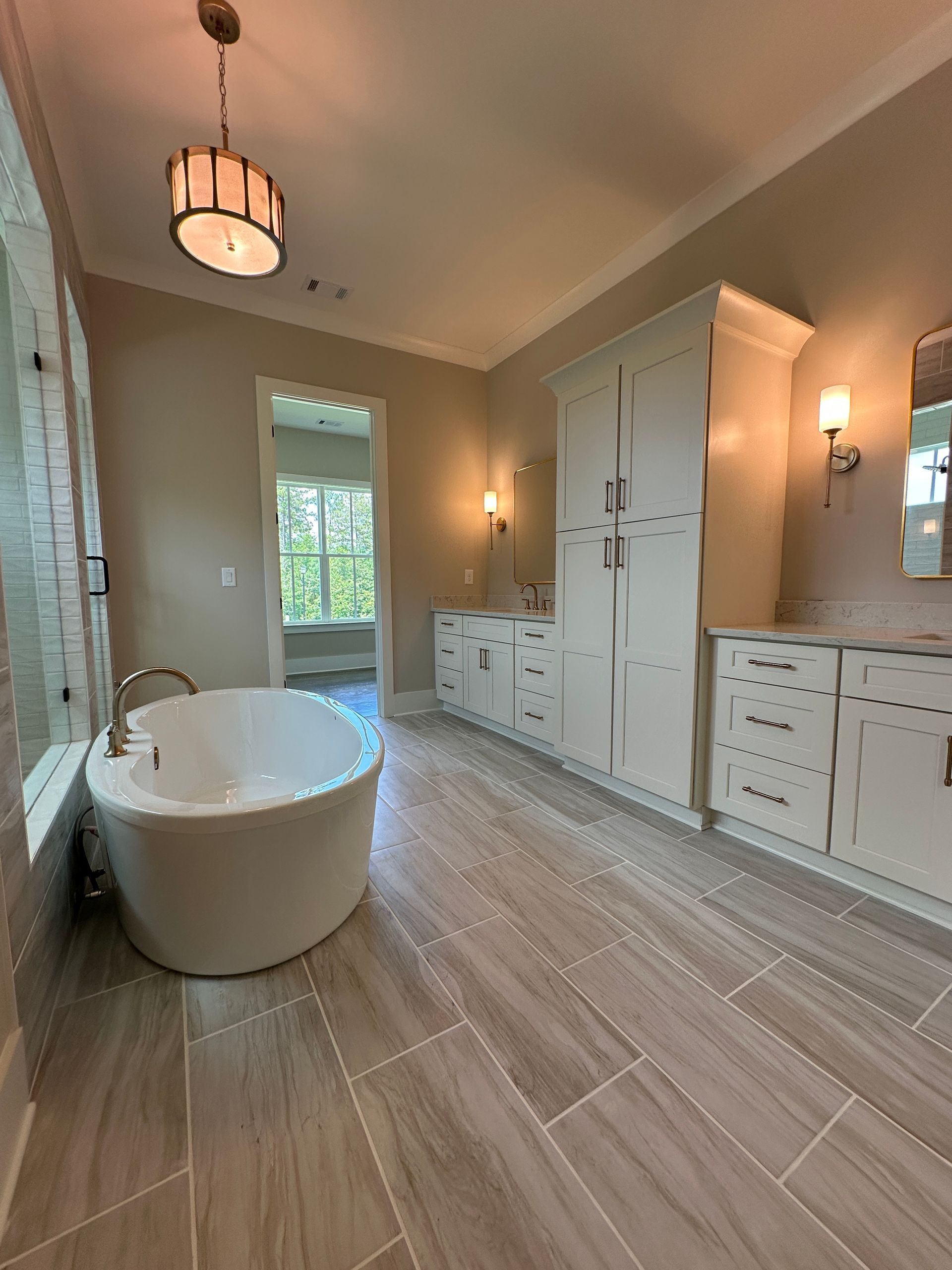Luxury bathroom with freestanding tub, double vanity, large cabinet, and tiled floor in warm neutral tones