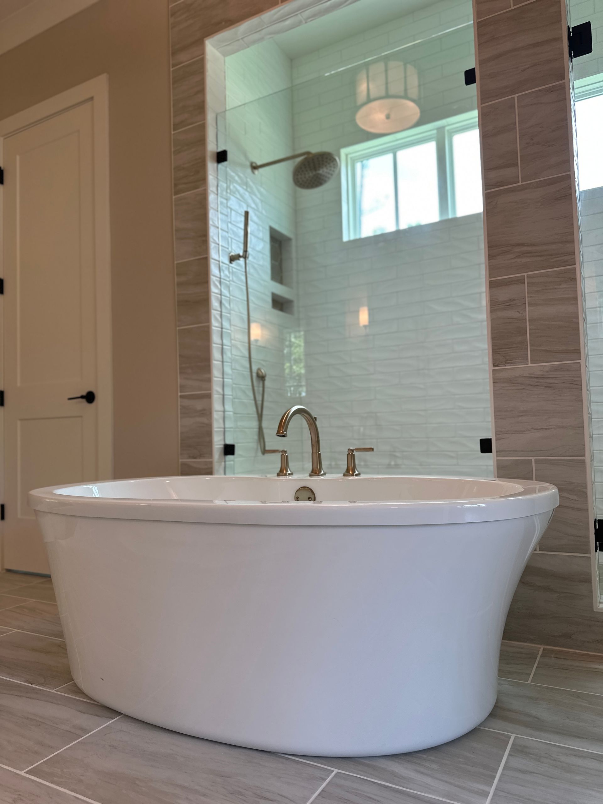 Modern bathroom with a freestanding white tub, glass shower, and tiled walls