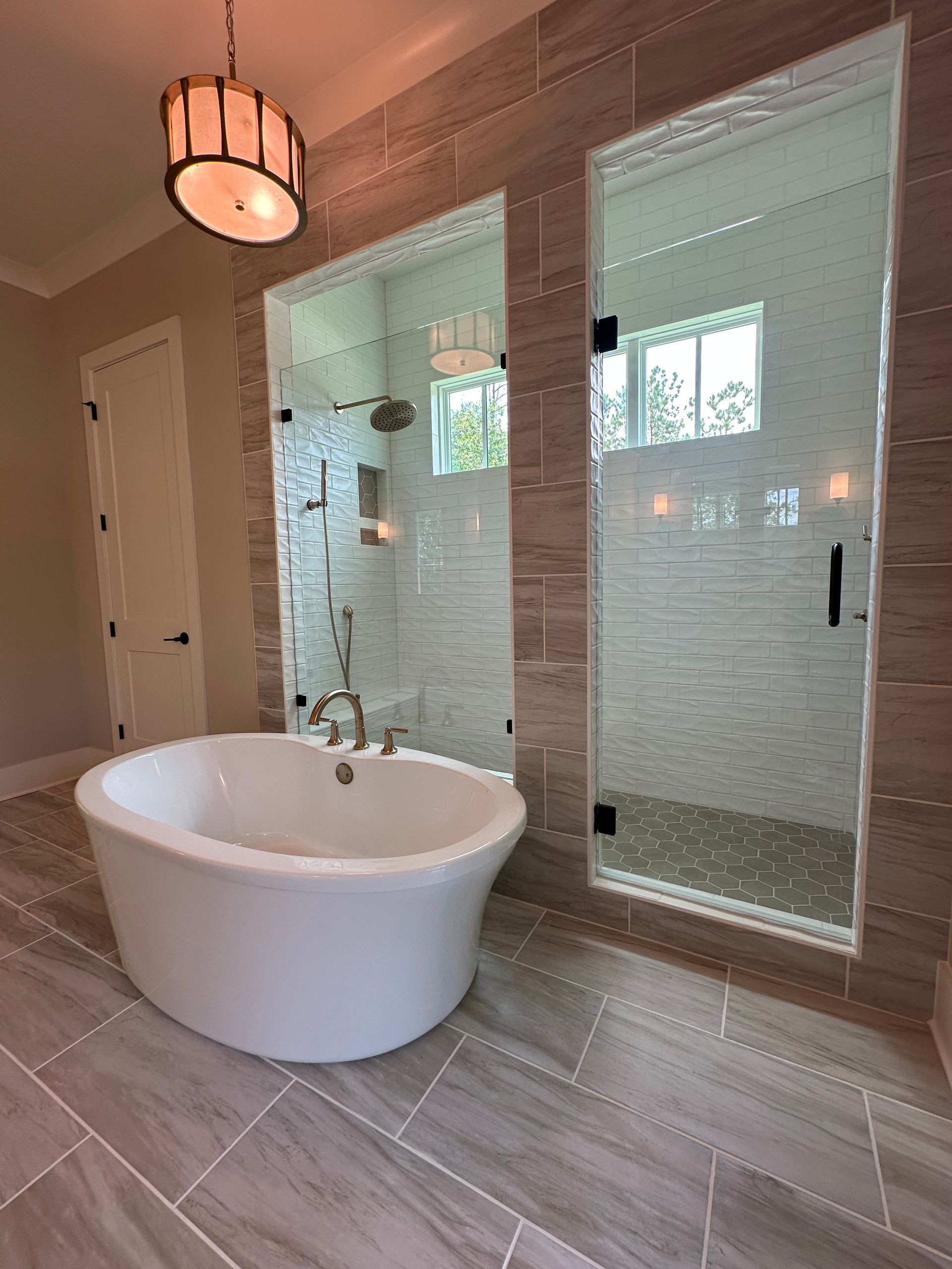 Modern bathroom with a freestanding tub, glass shower, and large tiled floor in neutral tones
