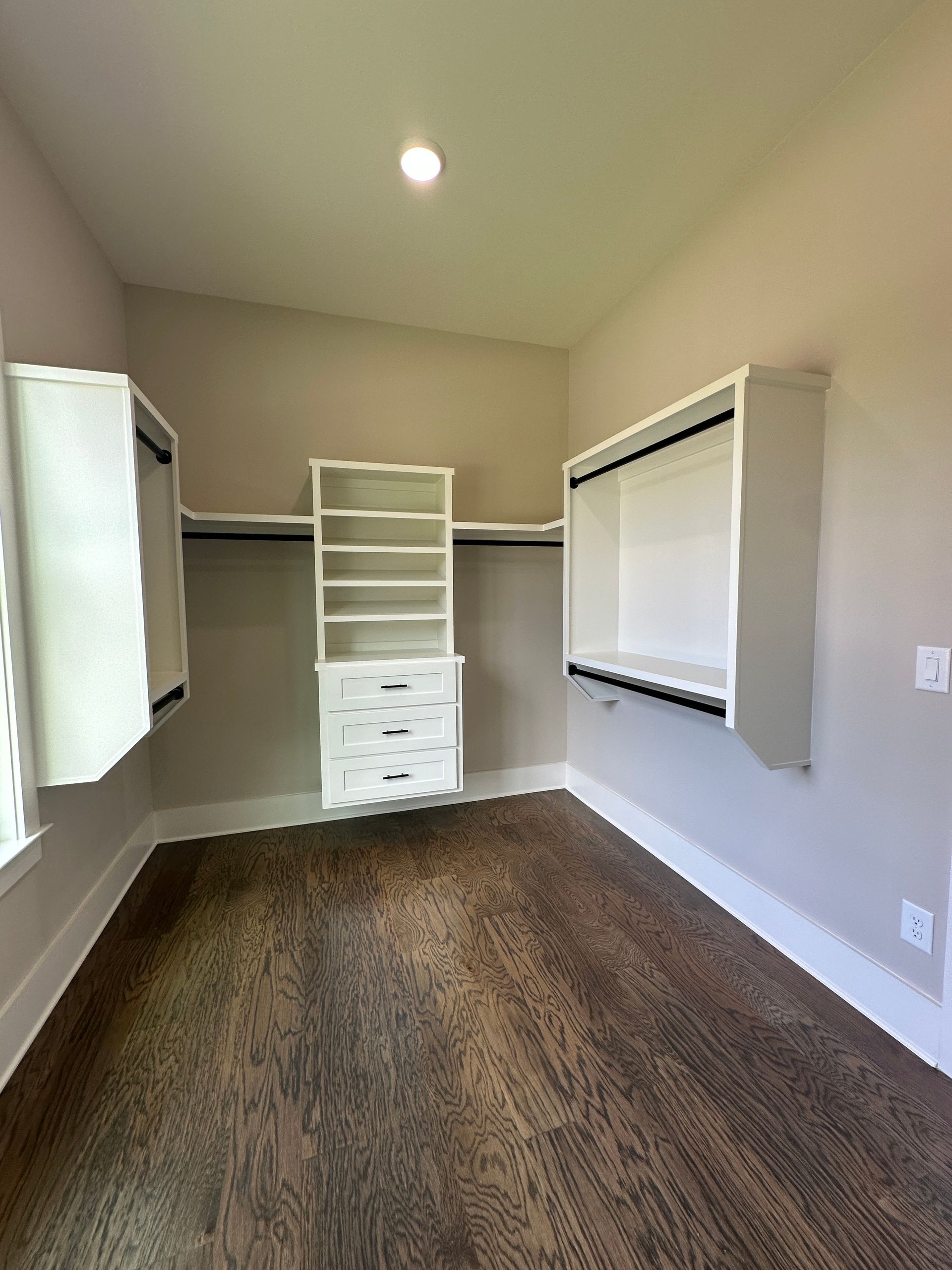 Empty walk-in closet with shelves, hanging rods, drawers, and a carpeted floor.