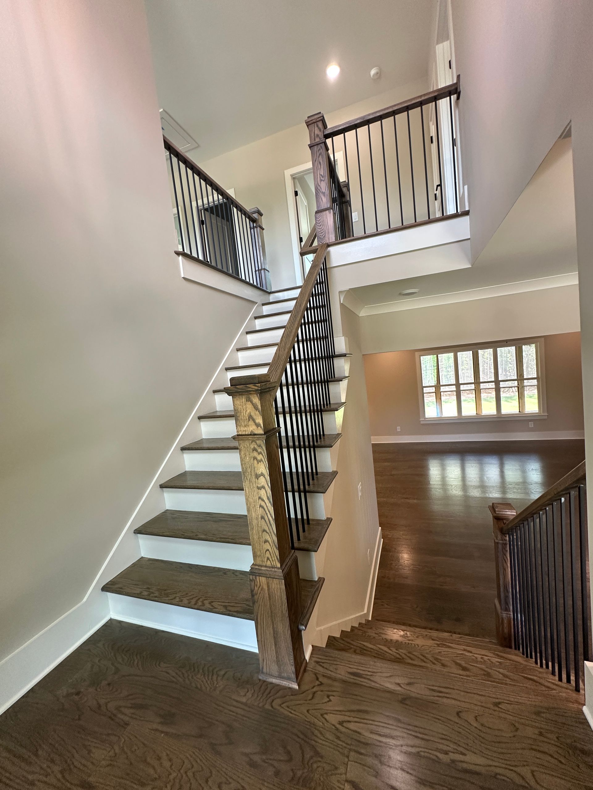Staircase with dark wood railing, carpeted steps, and a bright landing in a two-story home