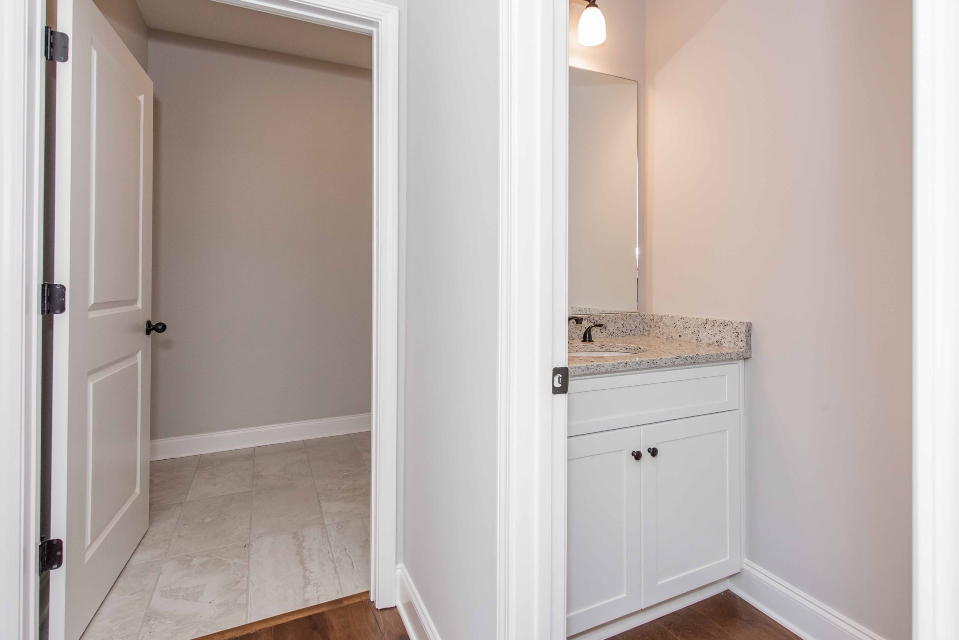 Bathroom vanity and adjacent closet with white trim, beige walls, and hardwood floors