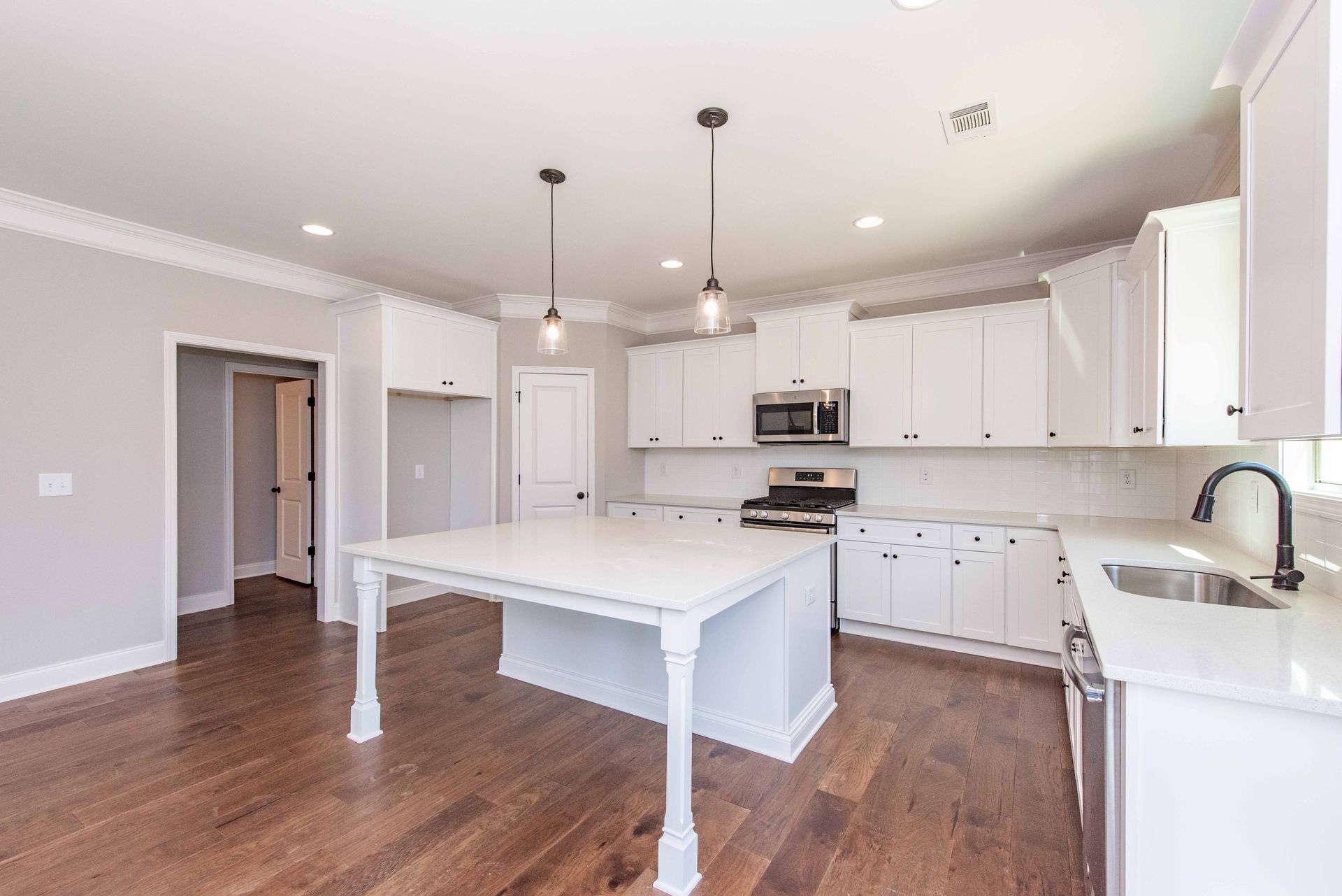 Bright white modern kitchen with island, pendant lights, and wood floors
