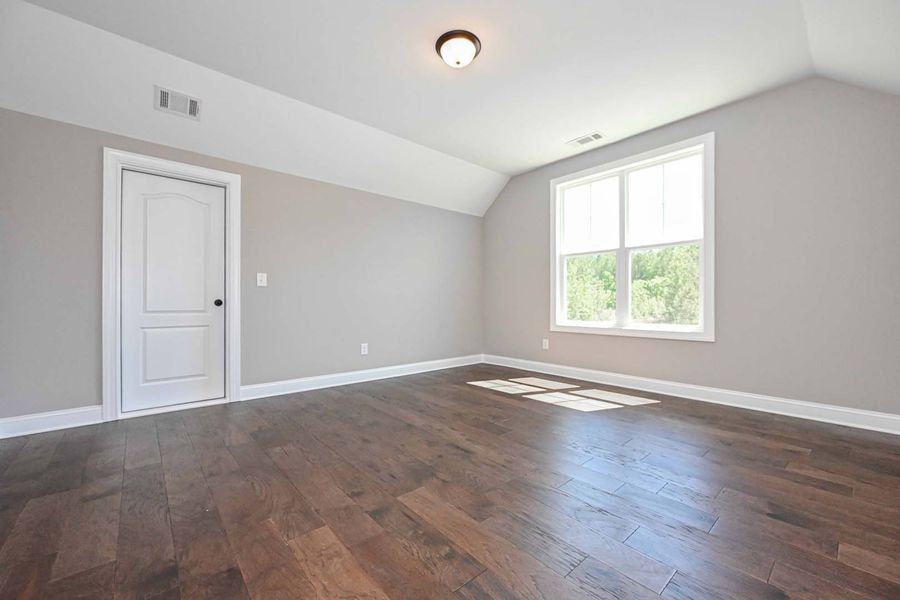 Empty room with gray walls, white door and trim, and dark wood floors.