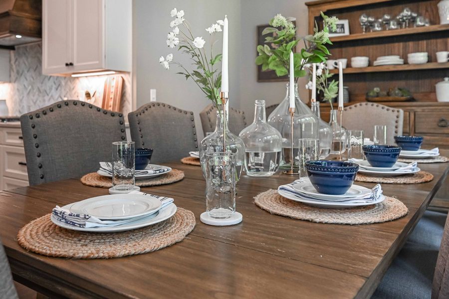 Dining table set for a meal, with floral centerpiece and blue and white place settings.