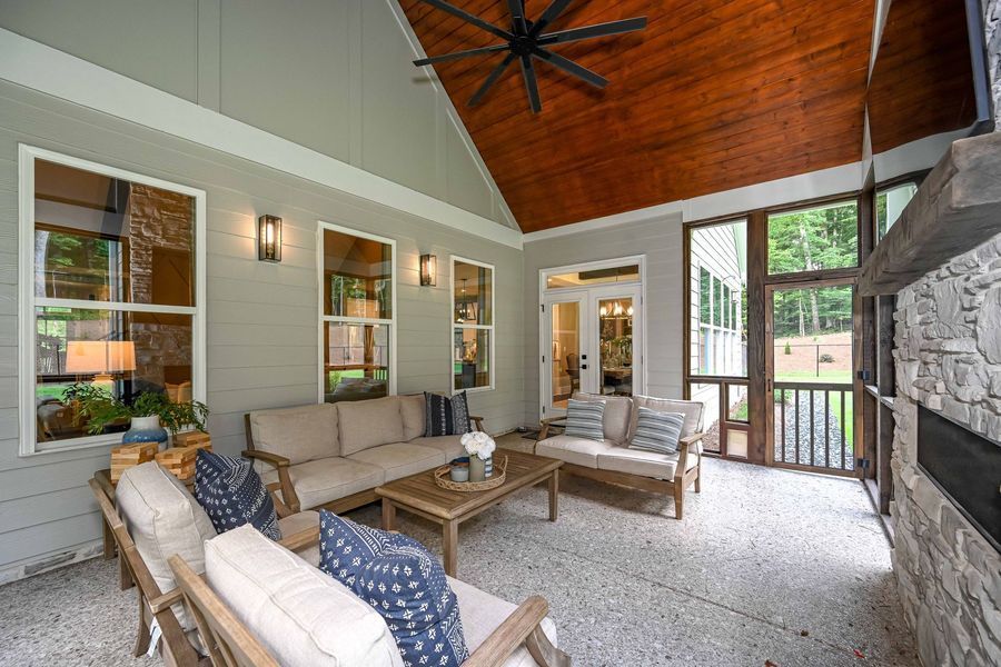 Outdoor living room with seating, fireplace, and wood ceiling.