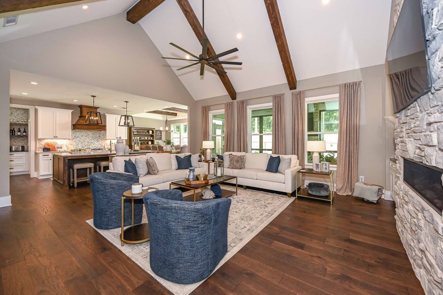 Living room with vaulted ceiling, wooden beams, sofas, and fireplace.
