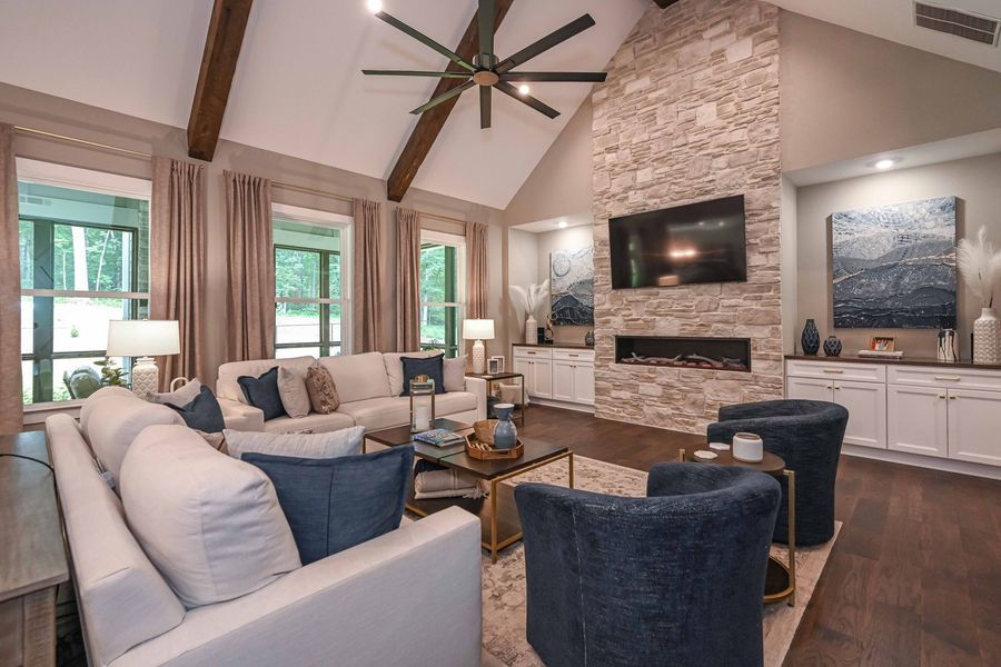 Living room with stone fireplace, white sofas, blue chairs, and dark wood floors.