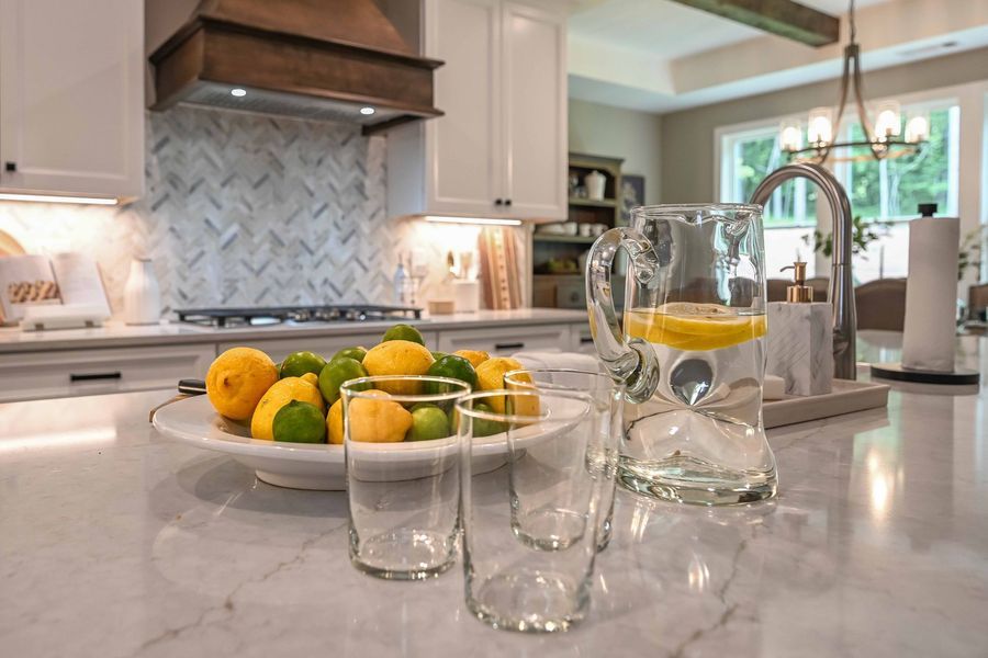 Kitchen countertop with a bowl of citrus, glasses, and a pitcher of water with lemon slices.