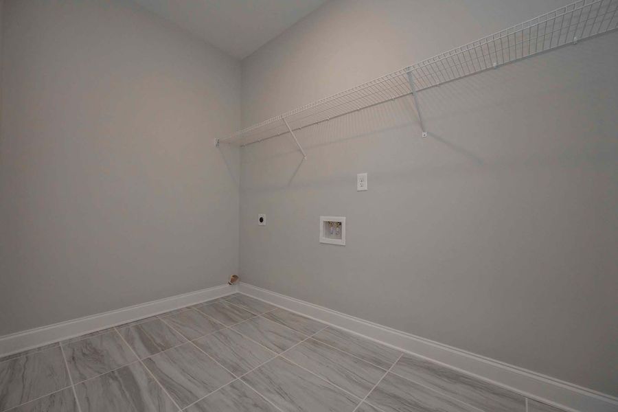 Empty laundry room with gray walls, tile floor, and wire shelving.