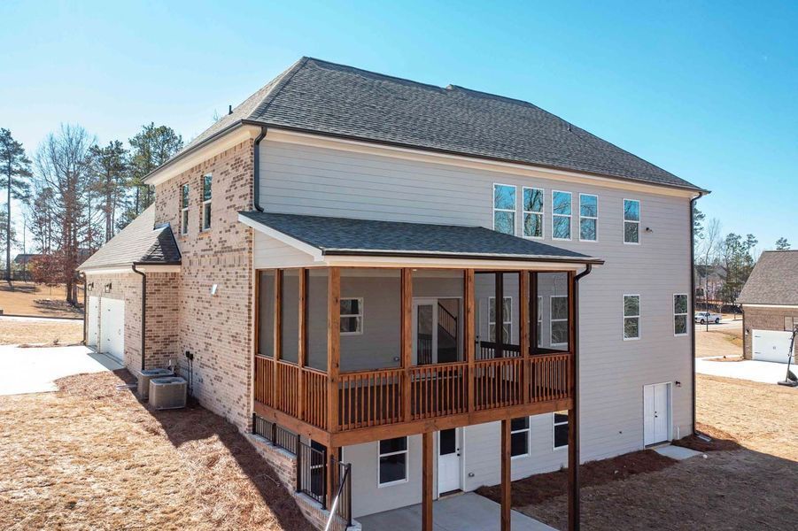 Back of a two-story house with a screened porch. Brick and gray siding, wood deck, and blue sky.
